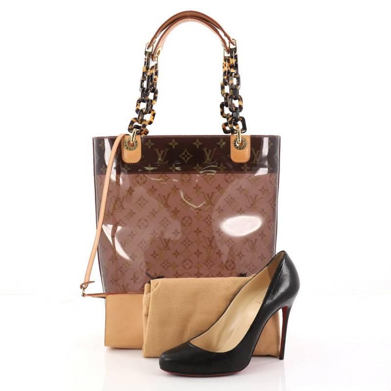 This authentic Louis Vuitton Sac Ambre Handbag Monogram Vinyl MM showcases a playful design perfect for casual days. Constructed from brown monogram vinyl and accented with cowhide leather trims, this bag features tortoise shell-patterned lucite