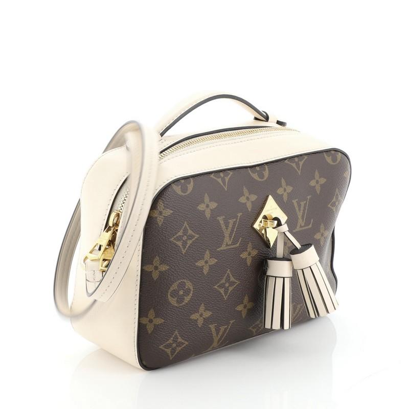 This Louis Vuitton Saintonge Handbag Monogram Canvas with Leather, crafted from brown monogram coated canvas with neutral leather, features top handle and long strap, leather tassels and gold-tone hardware. Its zip closure opens to a neutral fabric