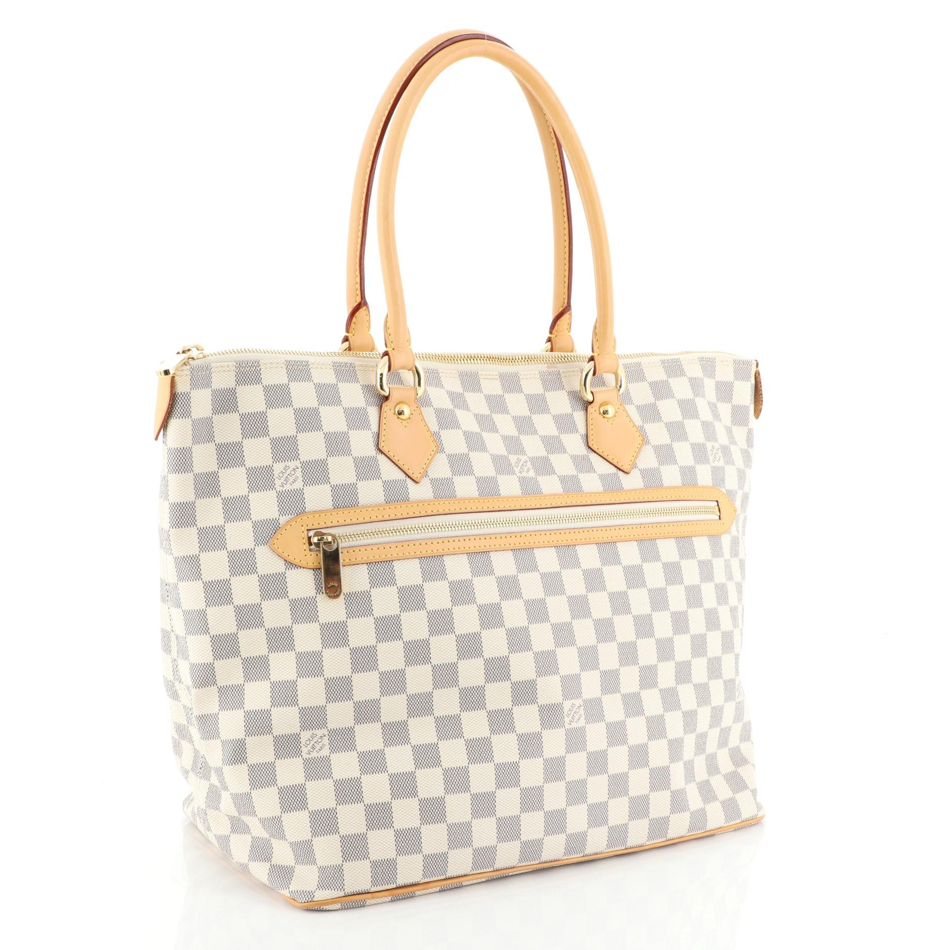 This Louis Vuitton Saleya Handbag Damier GM, crafted in damier azur coated canvas, features dual rolled leather handles, leather trim, exterior front zip pocket, and gold-tone hardware. Its top zip closure opens to a neutral microfiber interior with