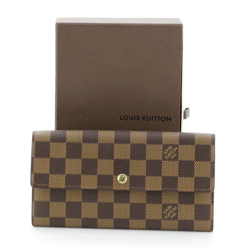 This Louis Vuitton Sarah Wallet Damier, crafted in damier ebene coated canvas, features gold-tone hardware. Its snap button closure opens to a brown leather interior with middle zip compartment. Authenticity code reads: CA1025. 

Estimated Retail