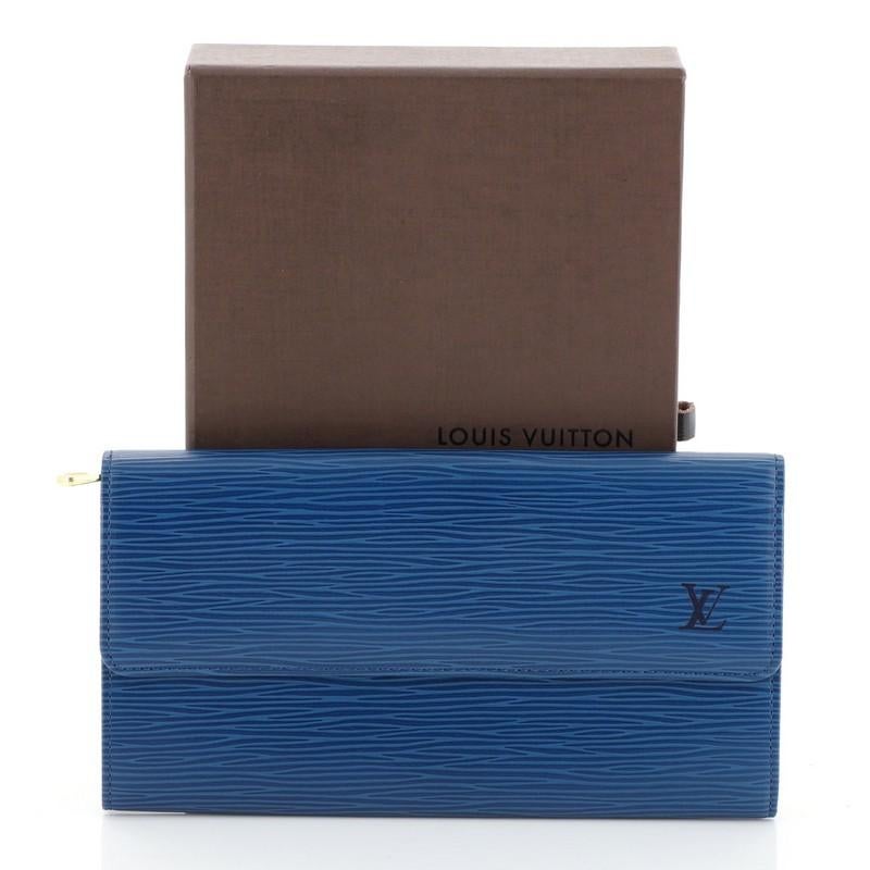 This Louis Vuitton Sarah Wallet Epi Leather, crafted from blue epi leather, features subtle stamped LV logo on its flap, snap button closure, and silver-tone hardware. Its snap button closure opens to a blue leather interior with multiple card