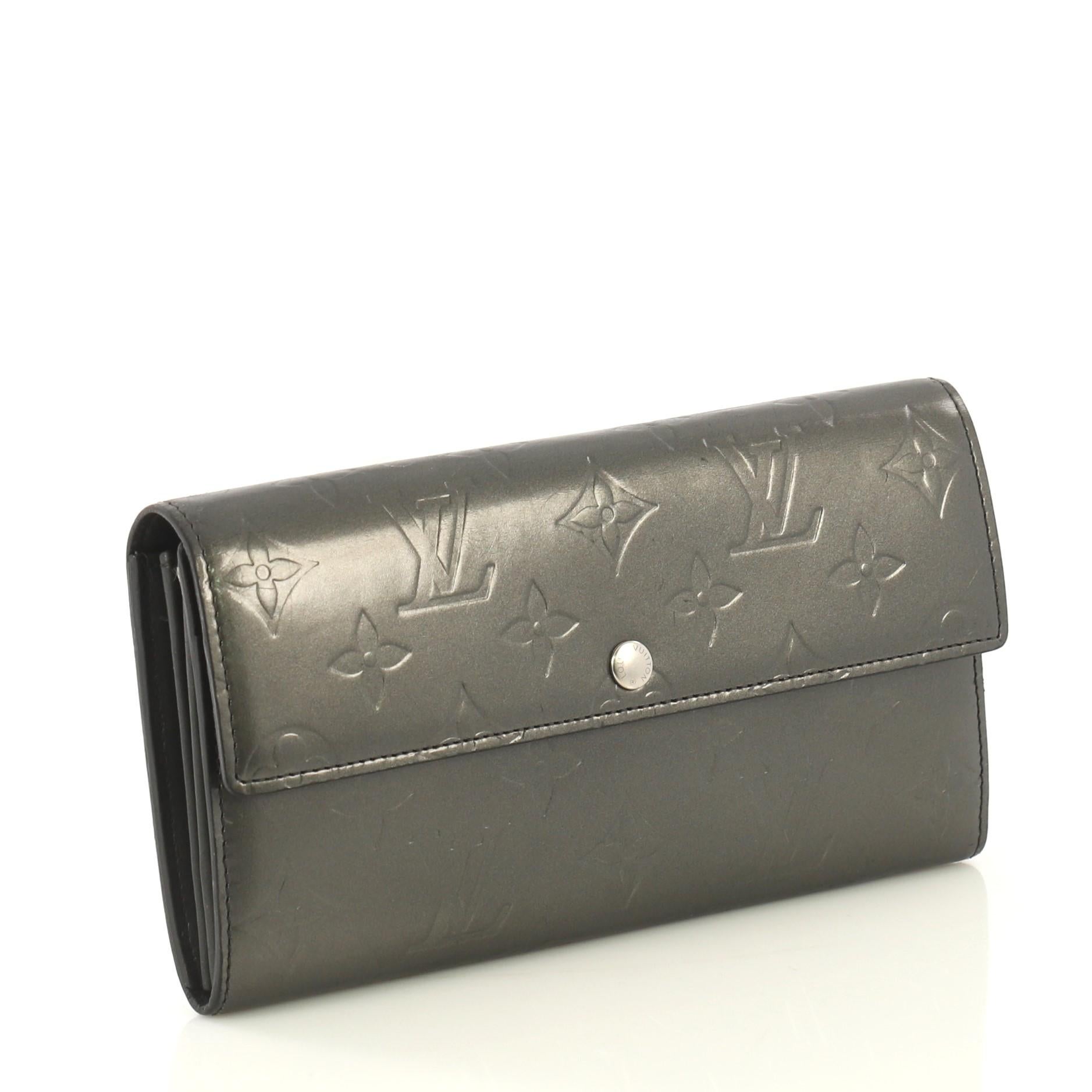 This Louis Vuitton Sarah Wallet Monogram Vernis, crafted in gray monogram vernis leather, features silver-tone hardware. Its snap button closure opens to a gray leather interior with multiple card slots and a middle zip compartment. Authenticity