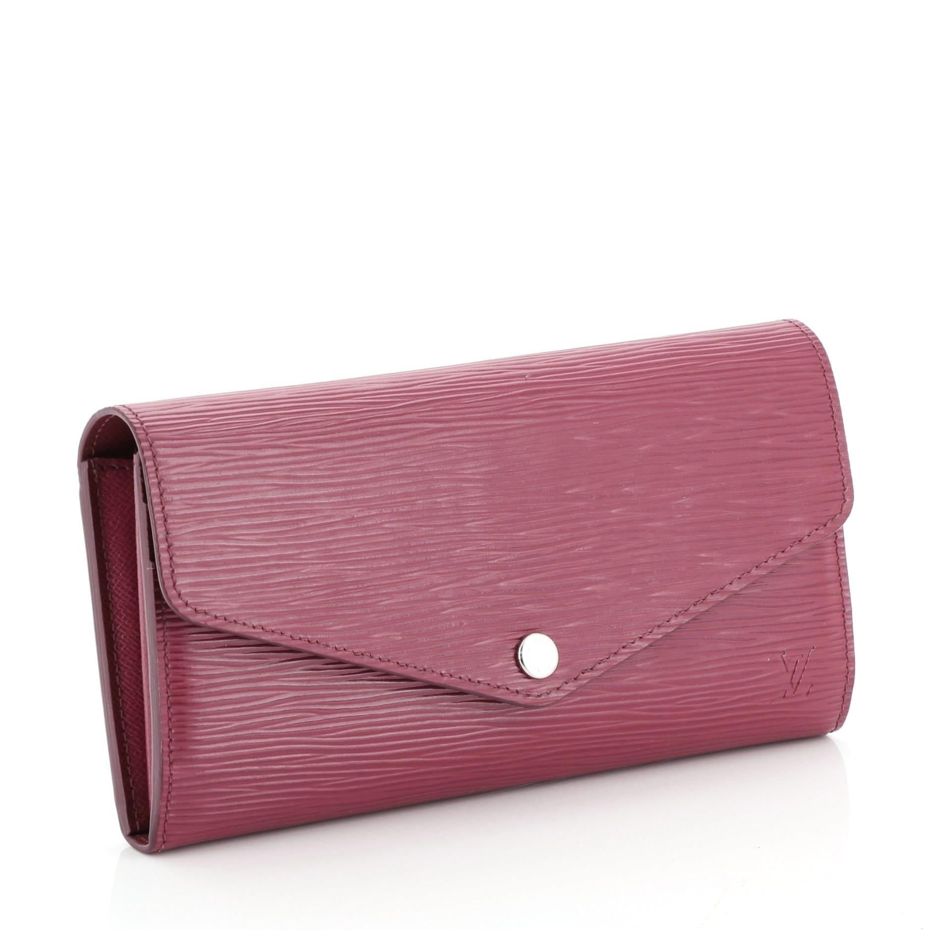 This Louis Vuitton Sarah Wallet NM Epi Leather is a perfect everyday accessory. Crafted from pink epi leather, it features an envelope-style frontal flap and silver-tone hardware. Its snap button closure opens to a pink leather interior with