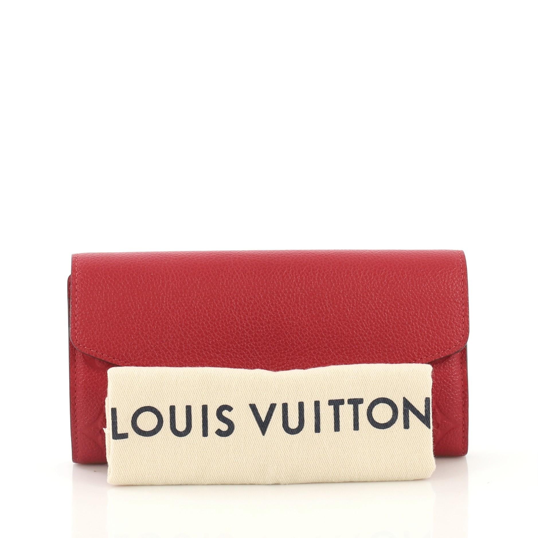 This Louis Vuitton Sarah Wallet NM Monogram Empreinte Leather, crafted from red monogram empreinte leather, features an envelope-style frontal flap and gold-tone hardware. Its snap button closure opens to a red leather interior with multiple card