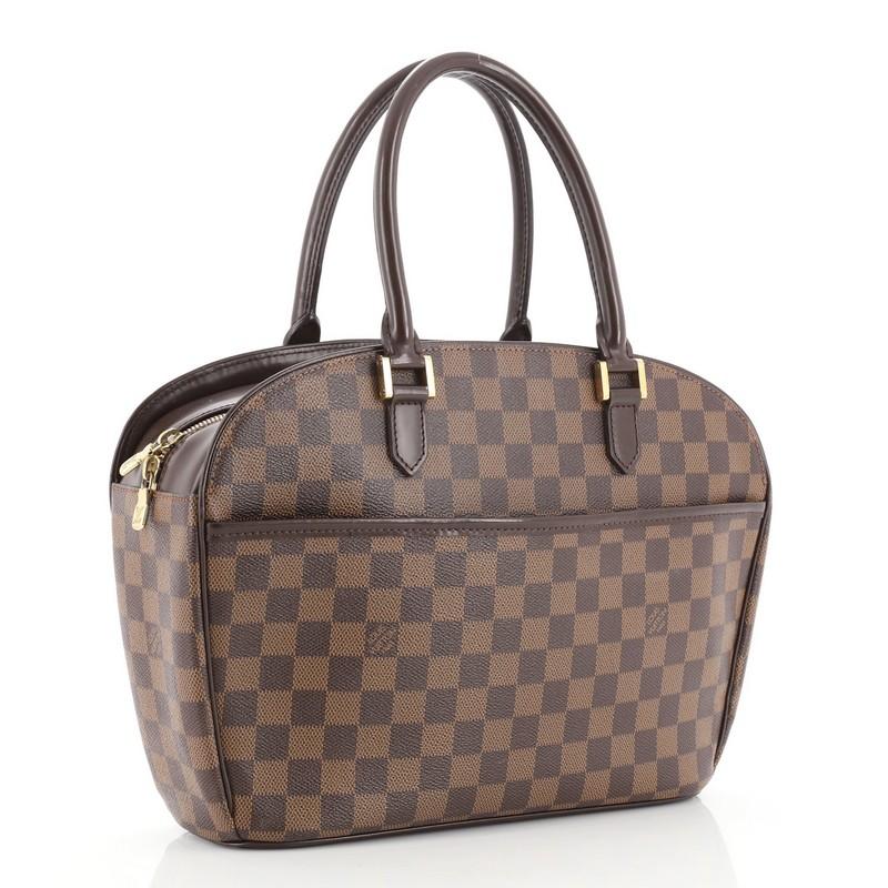 This Louis Vuitton Sarria Handbag Damier Horizontal, crafted in damier ebene coated canvas, features dual rolled leather handles, leather trim, exterior flat pocket, and gold-tone hardware. Its two-way zip closure opens to an orange microfiber