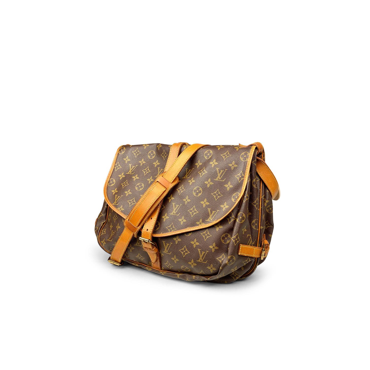 Brown and tan monogram coated canvas Louis Vuitton Saumur 35 with

- Brass hardware
- Tan vachetta trim
- Single flat shoulder strap featuring buckle adjustment
- Buckle expansions at sides
- Two compartments, tonal canvas lining, three slip pockets