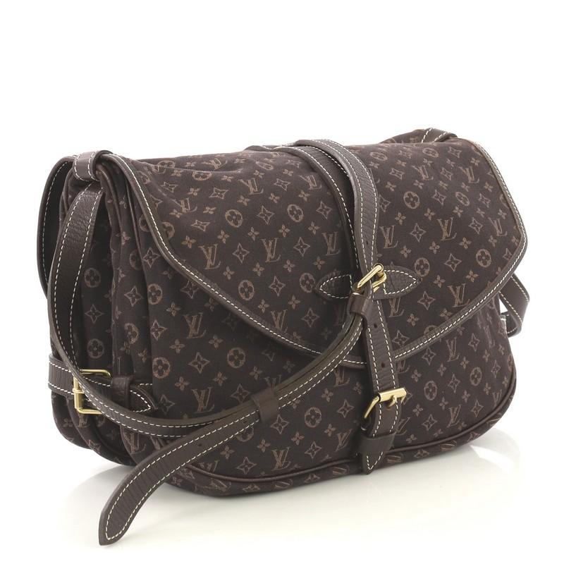 This Louis Vuitton Saumur Handbag Mini Lin, crafted in brown mini lin monogram canvas, features an adjustable leather crossbody strap, leather trim, and gold-tone hardware. Its buckle closure opens to brown fabric interior with slip compartments.