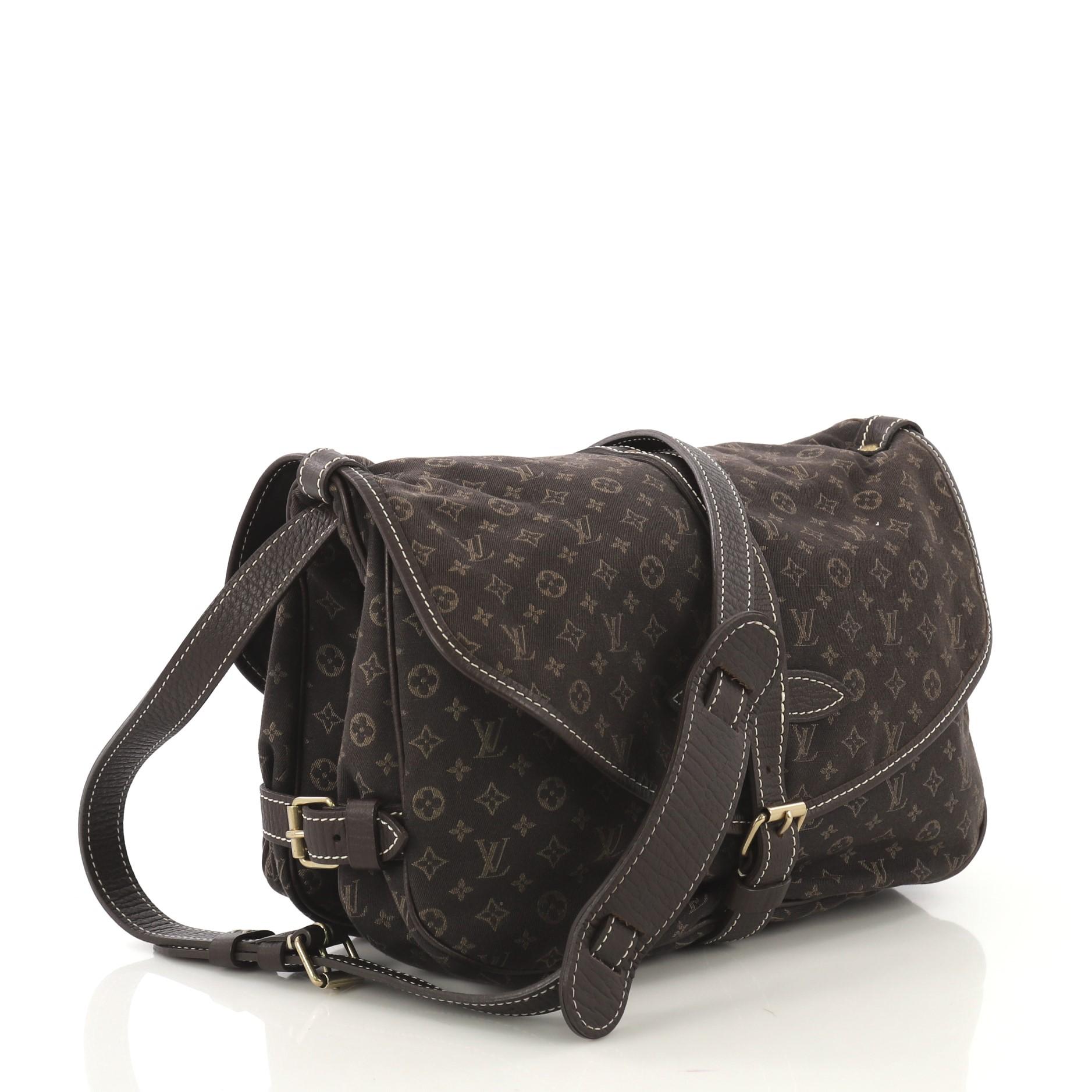 This Louis Vuitton Saumur Handbag Mini Lin, crafted in brown mini lin monogram canvas, features an adjustable leather crossbody strap, leather trim, and gold-tone hardware. Its buckle closure opens to brown fabric interior with slip compartments.