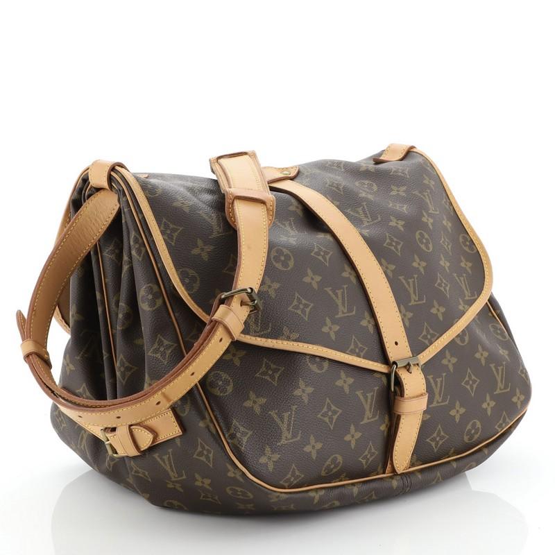 This Louis Vuitton Saumur Handbag Monogram Canvas 35, crafted in brown monogram coated canvas, features adjustable strap, double saddle compartments, and gold-tone hardware. Its buckle closure opens to a brown fabric interior with slip pockets.