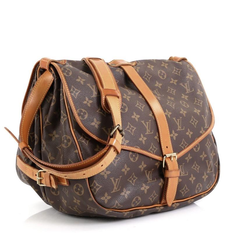 This Louis Vuitton Saumur Handbag Monogram Canvas 35, crafted in brown monogram coated canvas, features adjustable strap, double saddle compartments, and gold-tone hardware. Its buckle closure opens to a brown fabric interior with slip pockets.