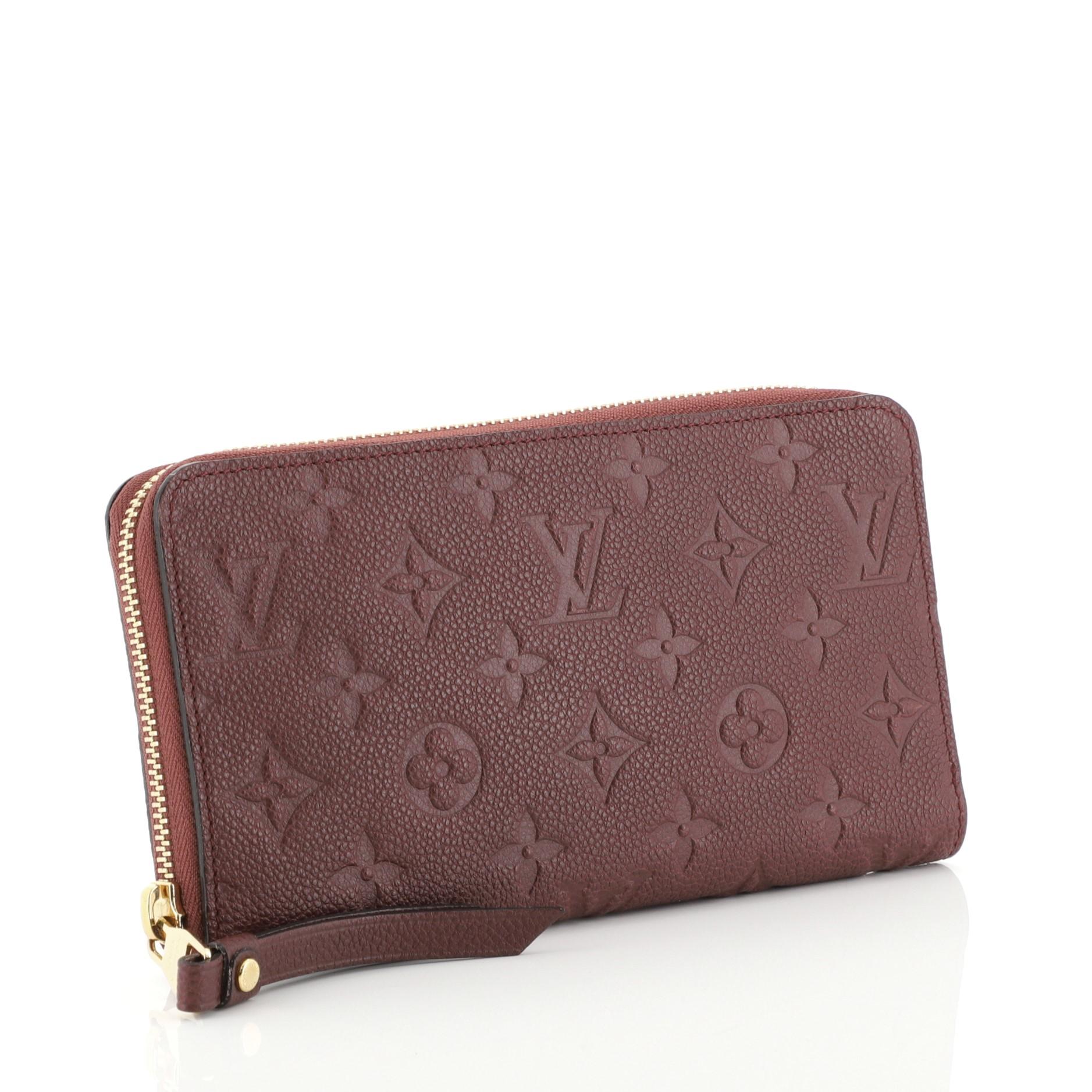 This Louis Vuitton Secret Wallet Monogram Empreinte Leather, crafted from red monogram empreinte leather, features gold-tone hardware. Its zip around closure opens to a red leather interior with multiple card slots and zip pocket. Authenticity code