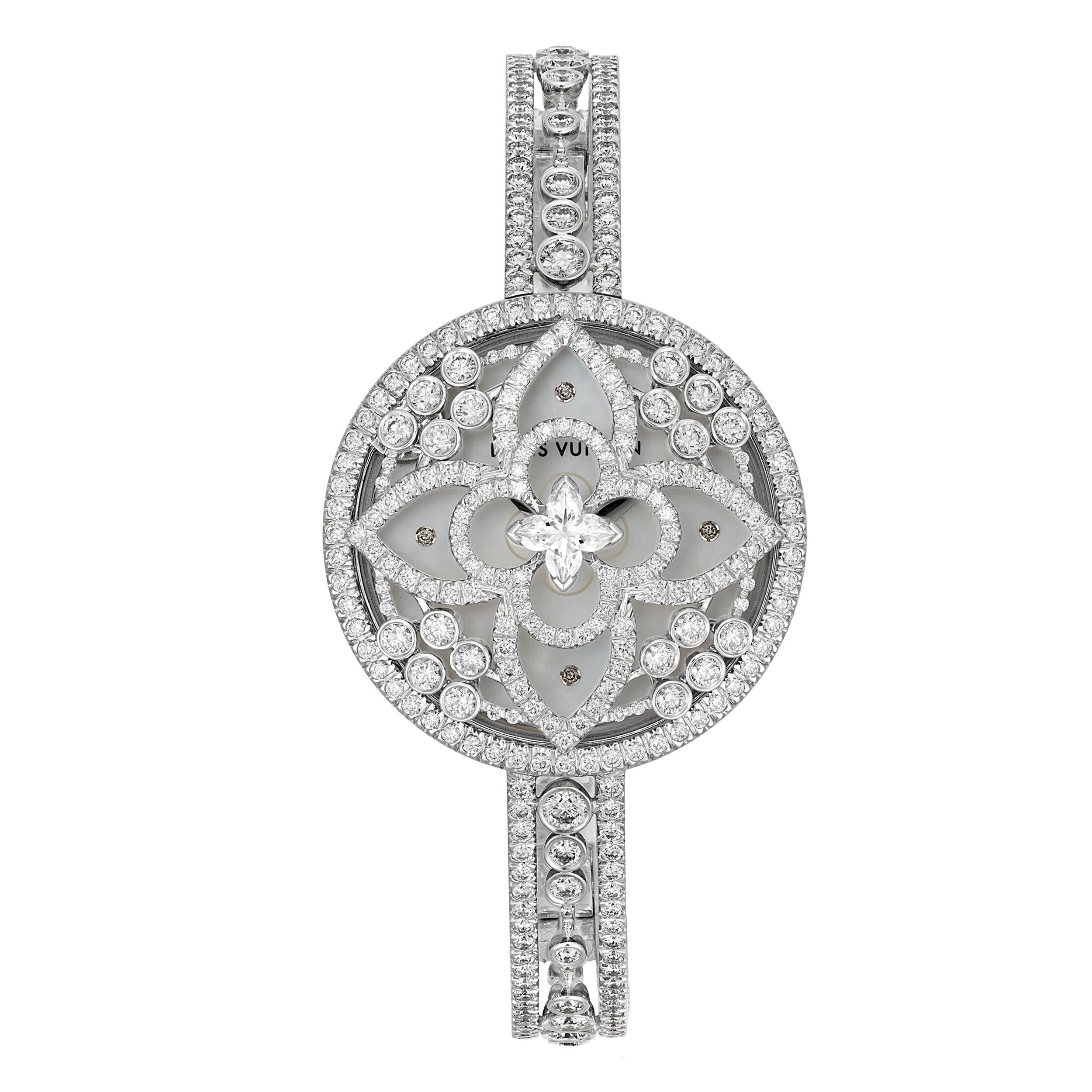 An unmistakable Louis Vuitton diamond watch showcasing a plethora of round brilliant cut diamonds 485, and one flower shaped diamond centrally located. 6.7ct TW This special and complicated designed diamond has more facets than a traditional round