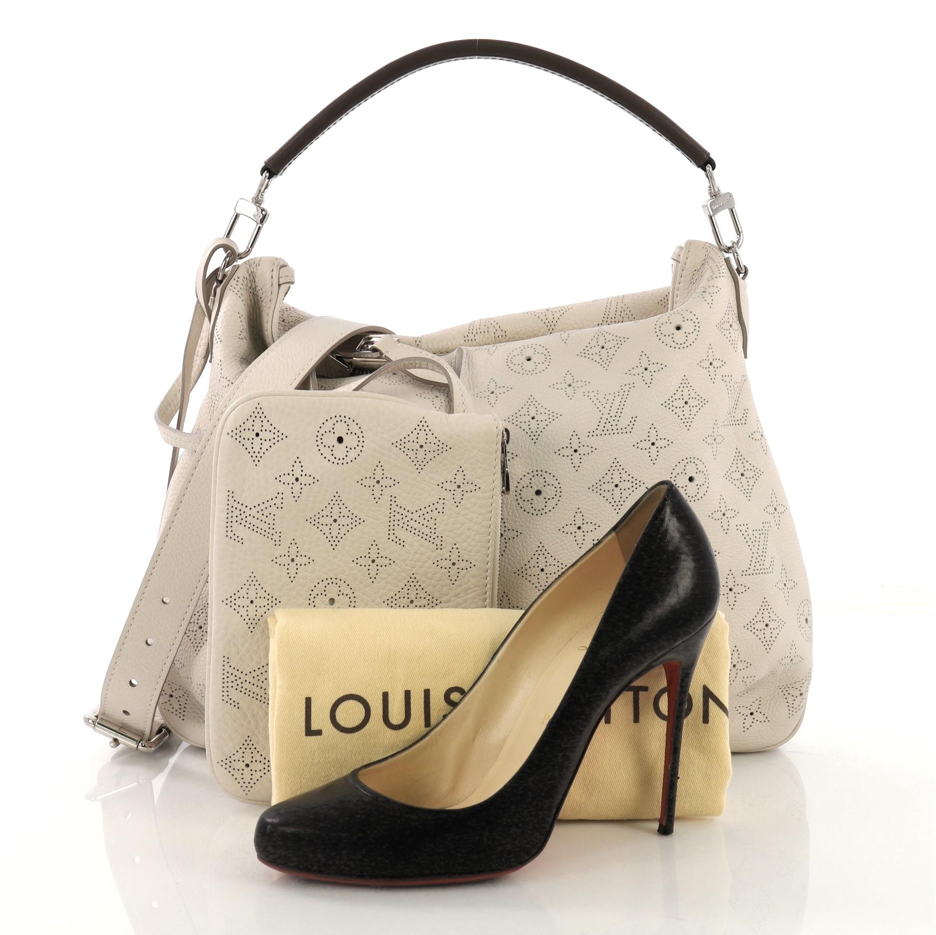 This Louis Vuitton Selene Handbag Mahina Leather PM, crafted in gray monogram perforated mahina leather, features a single loop leather handle, pleated detailing, and silver-tone hardware. Its top zip closure opens to a gray microfiber interior with