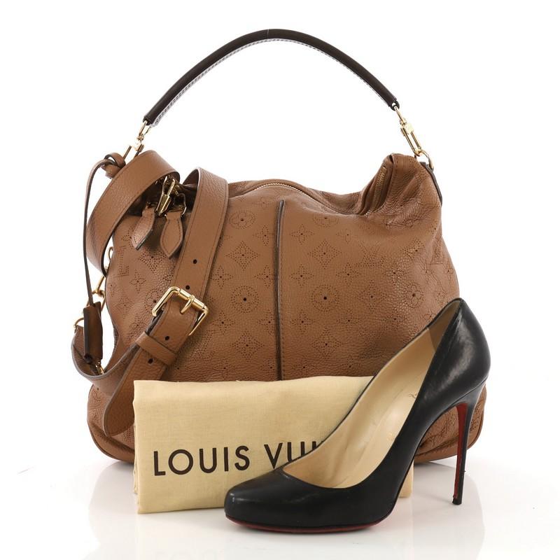 This Louis Vuitton Selene Handbag Mahina Leather PM, crafted from brown monogram perforated mahina leather, features a leather handle, pleated detailing, and gold-tone hardware. Its top zip closure opens to a dark brown microfiber interior with side
