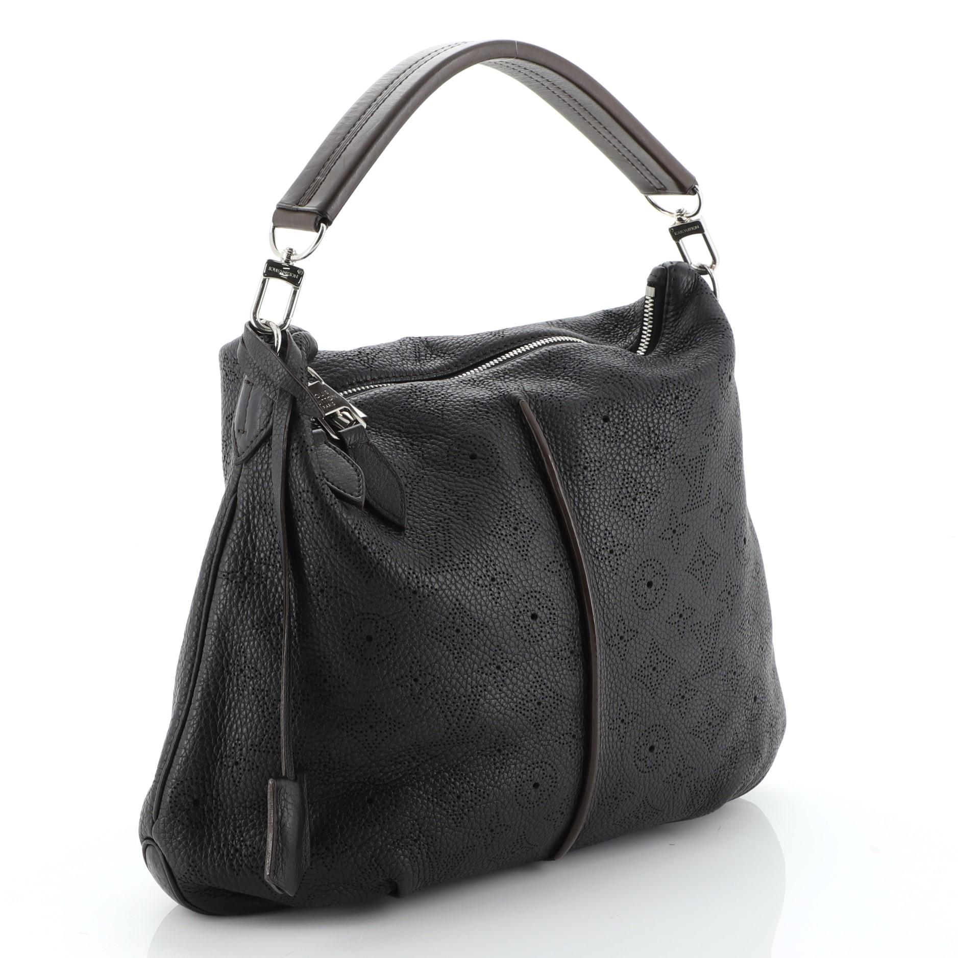 This Louis Vuitton Selene Handbag Mahina Leather PM, crafted from black monogram perforated mahina leather, features a leather handle, pleated detailing, and silver-tone hardware. Its zip closure opens to a brown microfiber interior with side zip