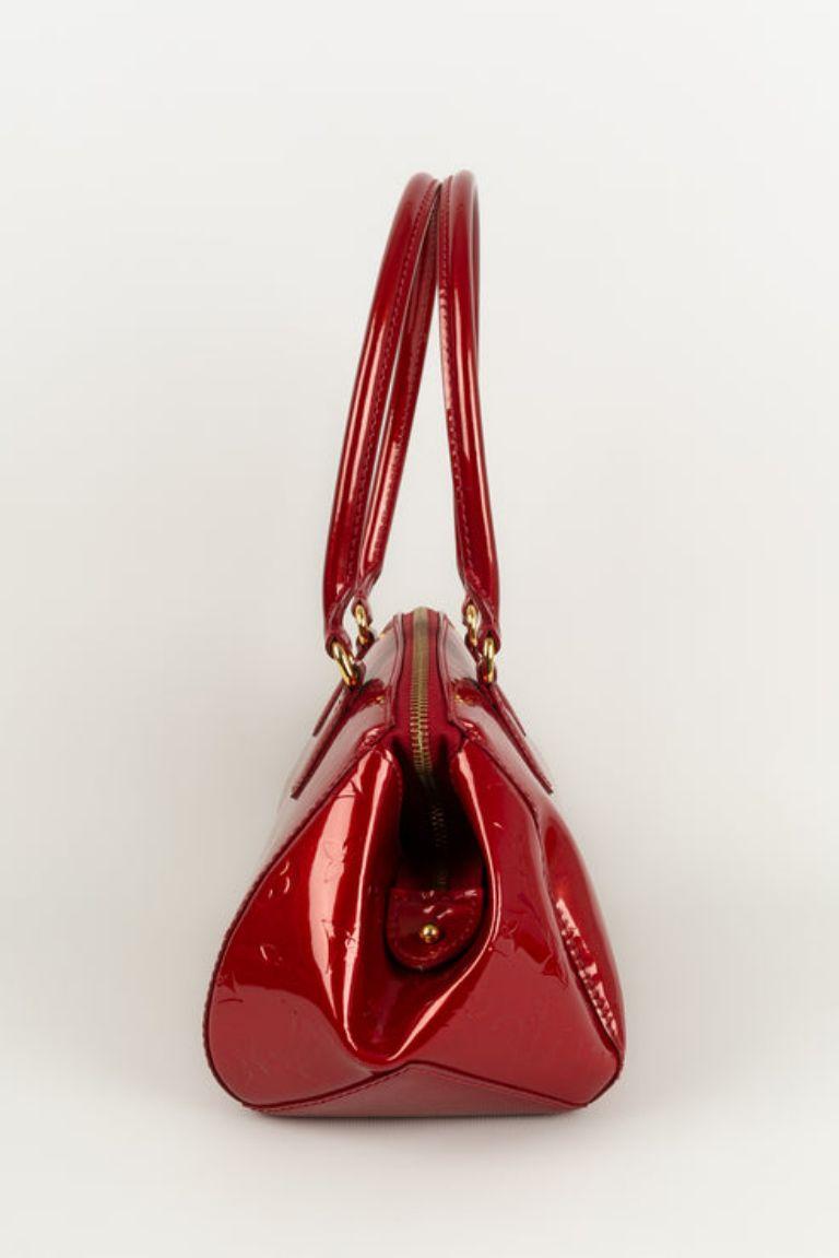 Louis Vuitton - (Made in France) Red patent leather bag with gold metal attributes.

Additional information: 
Dimensions: Height: 18 cm, Length: 26 cm, Depth: 12 cm, Handle: 55 cm
Condition: Very good condition
Seller Ref number: S216