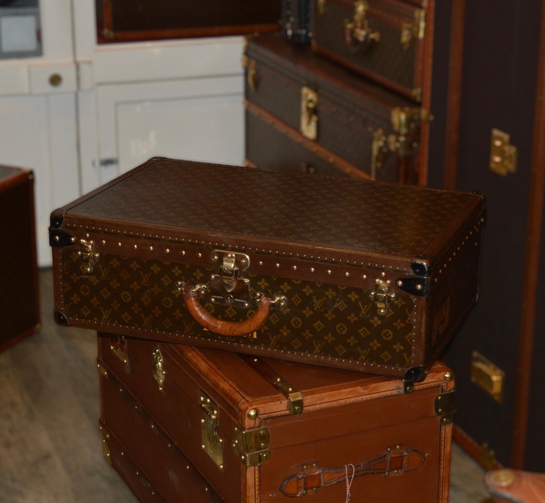 Superb and rare Alzer Louis Vuitton trunk covered with a canvas coated with a stencil monogram and protected by dark lozine borders. The case is equipped with a leather handle and three brass clasps stamped 