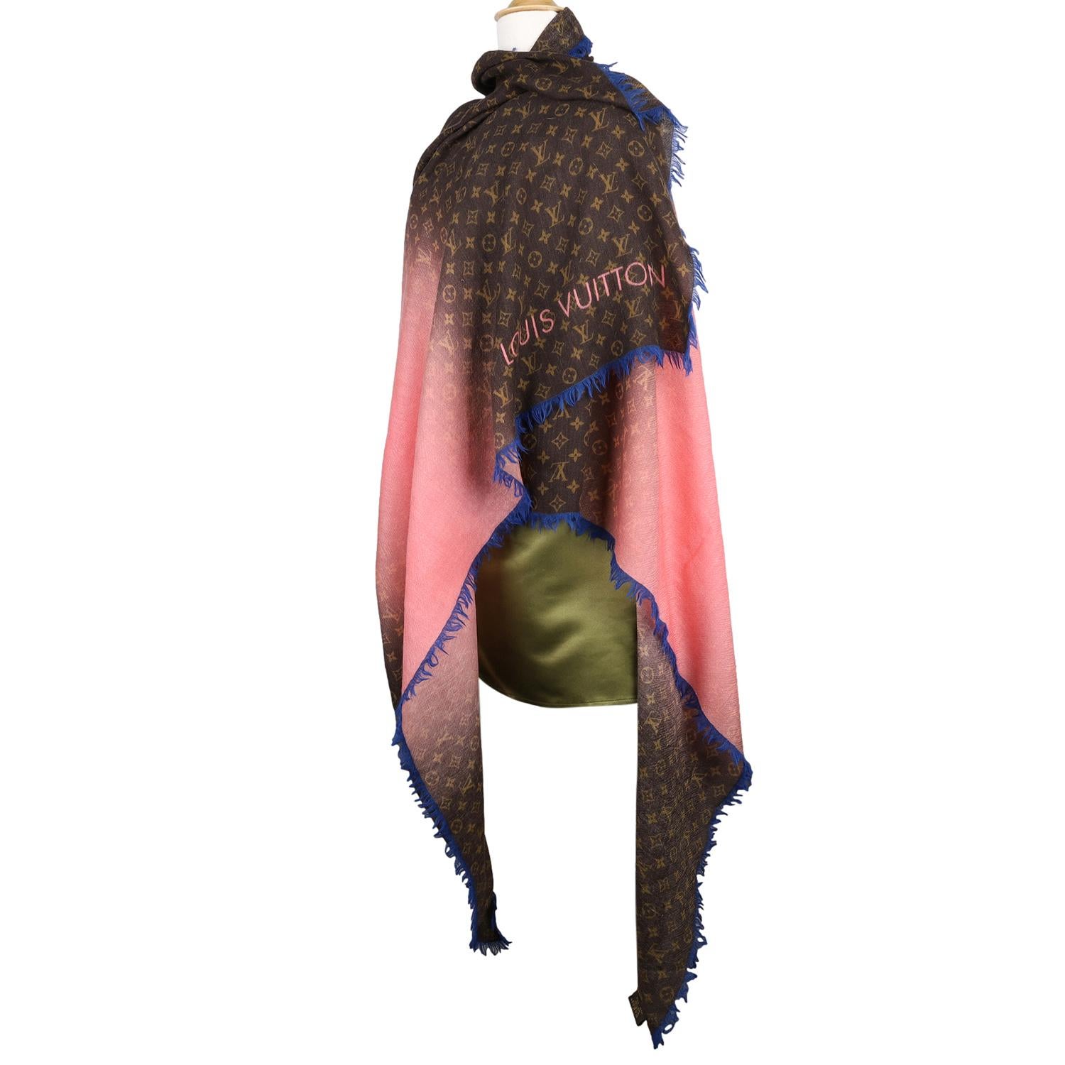 Autentico scialle o sciarpa Monogram di Louis Vuitton. Questa bellissima sciarpa è realizzata in lana e presenta l'iconico motivo Monogram in marrone su uno sfondo più scuro, con una sezione rosa/blu e frange blu. 

Goditi questa bellissima sciarpa