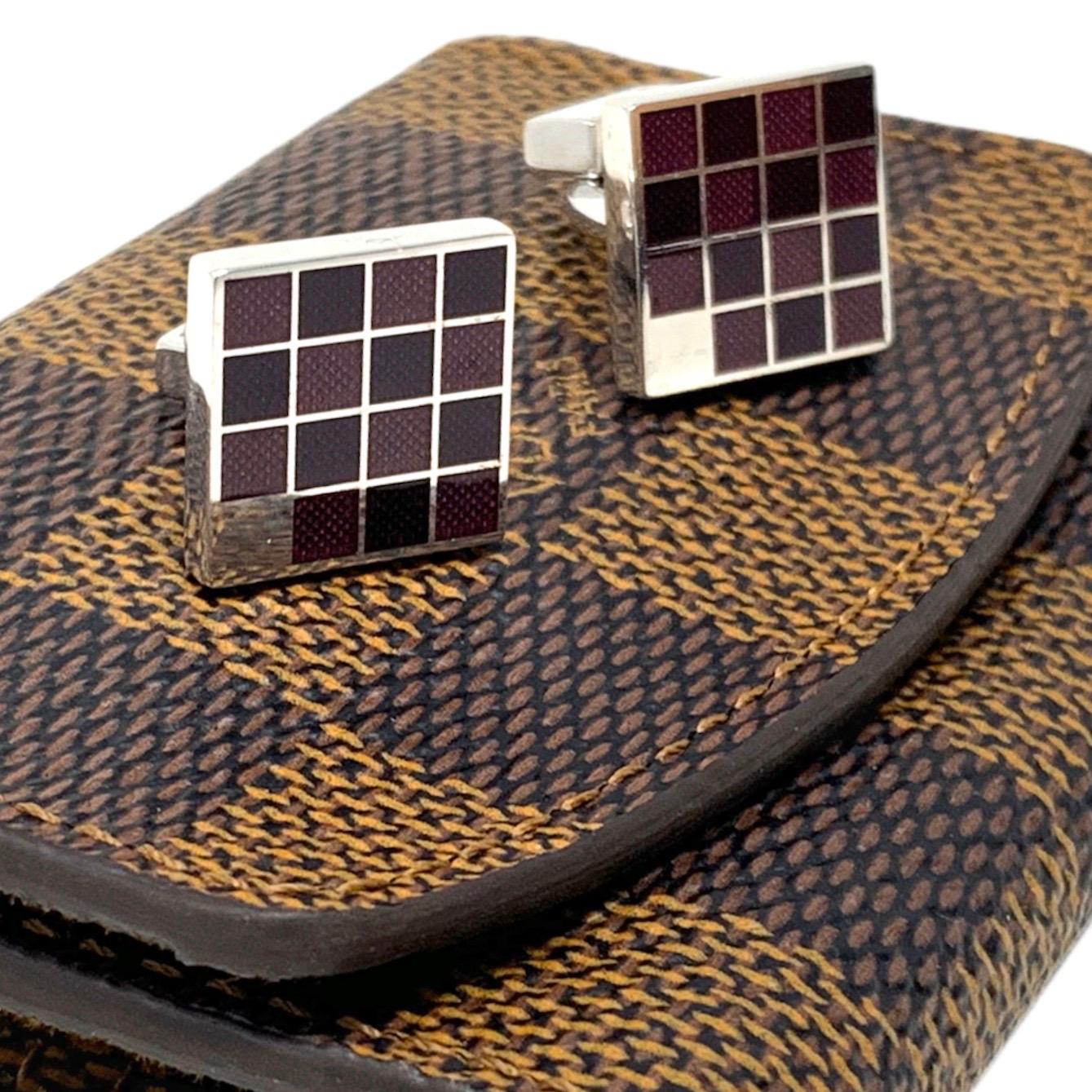 Classic Louis Vuitton silver-tone metal cufflinks with a square silhouette featuring multi-tone purple grid detailing. The set includes a Damier Ebene coated canvas carrying case, making these cufflinks easily portable and travel-ready.
Length: 0.5