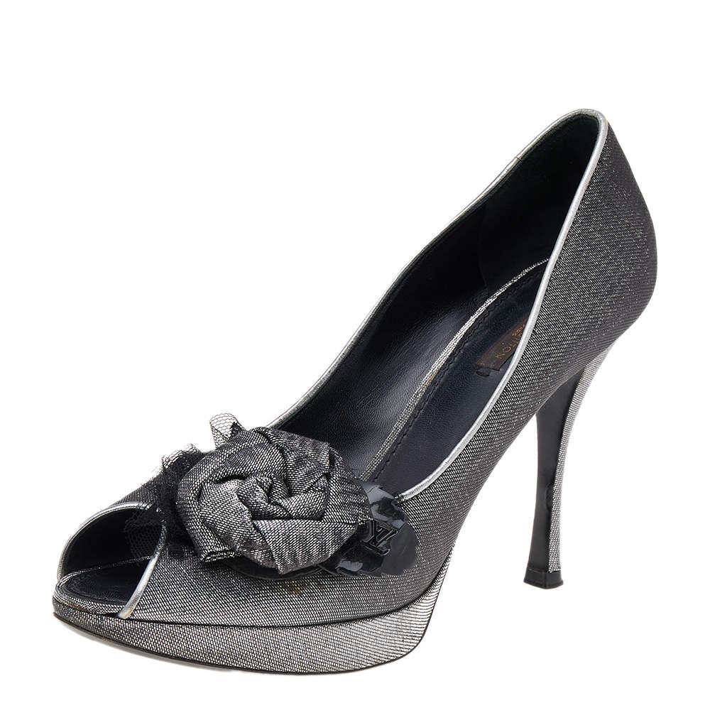 Stand out of the crowd by styling these gorgeous pumps from the House of  Louis Vuitton with your attire. They are designed lavishly using silver-black lurex fabric with a floral motif attached to the front. These LV pumps showcase peep-toes, a chic