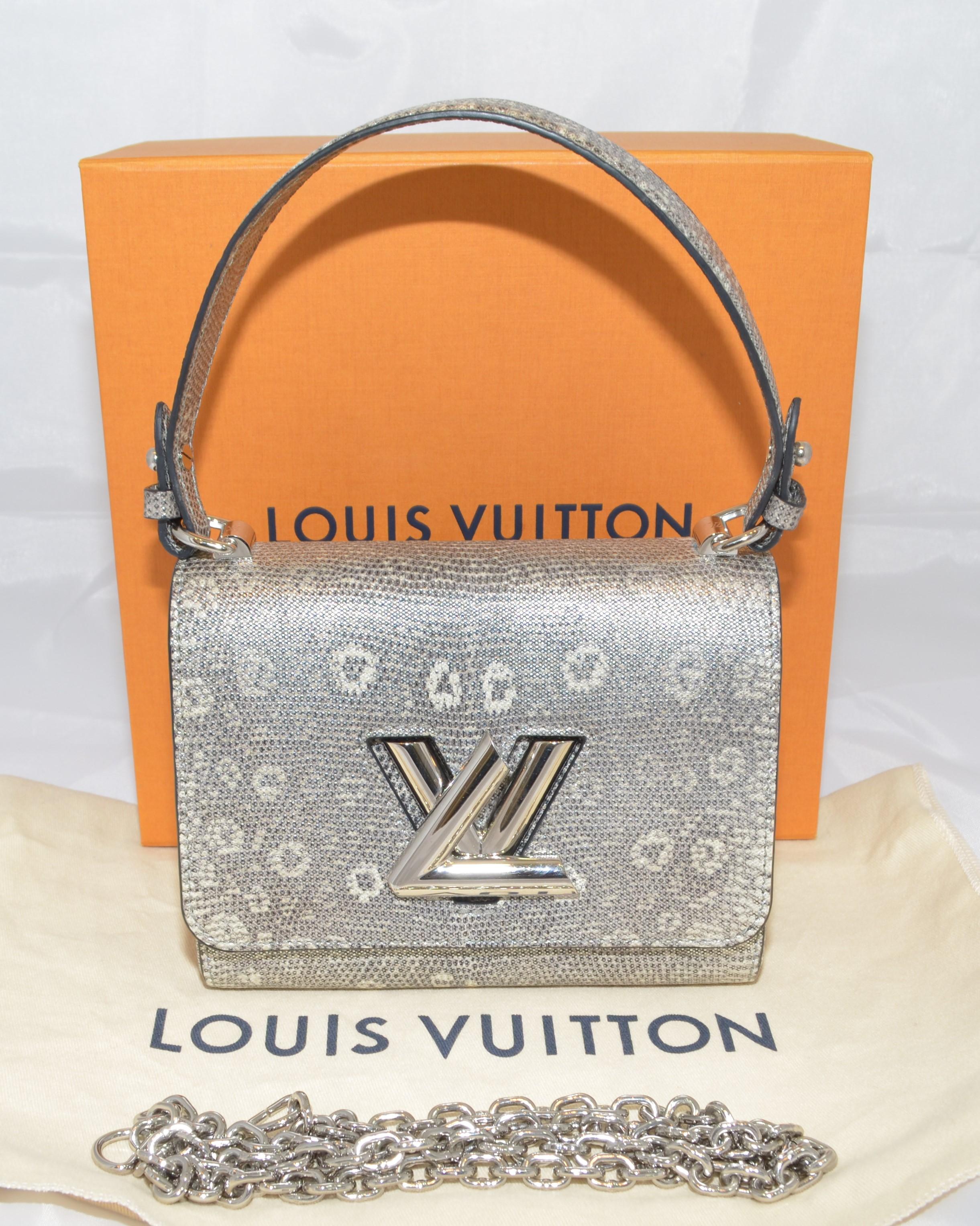 Louis Vuitton Twist PM bag featured in a silver-colored lizard skin with a convertible top or chain handle with a twist LV closure. Interior is lined in black leather and has one slip pocket. Handbag is in wonderful pre-owned condition with the