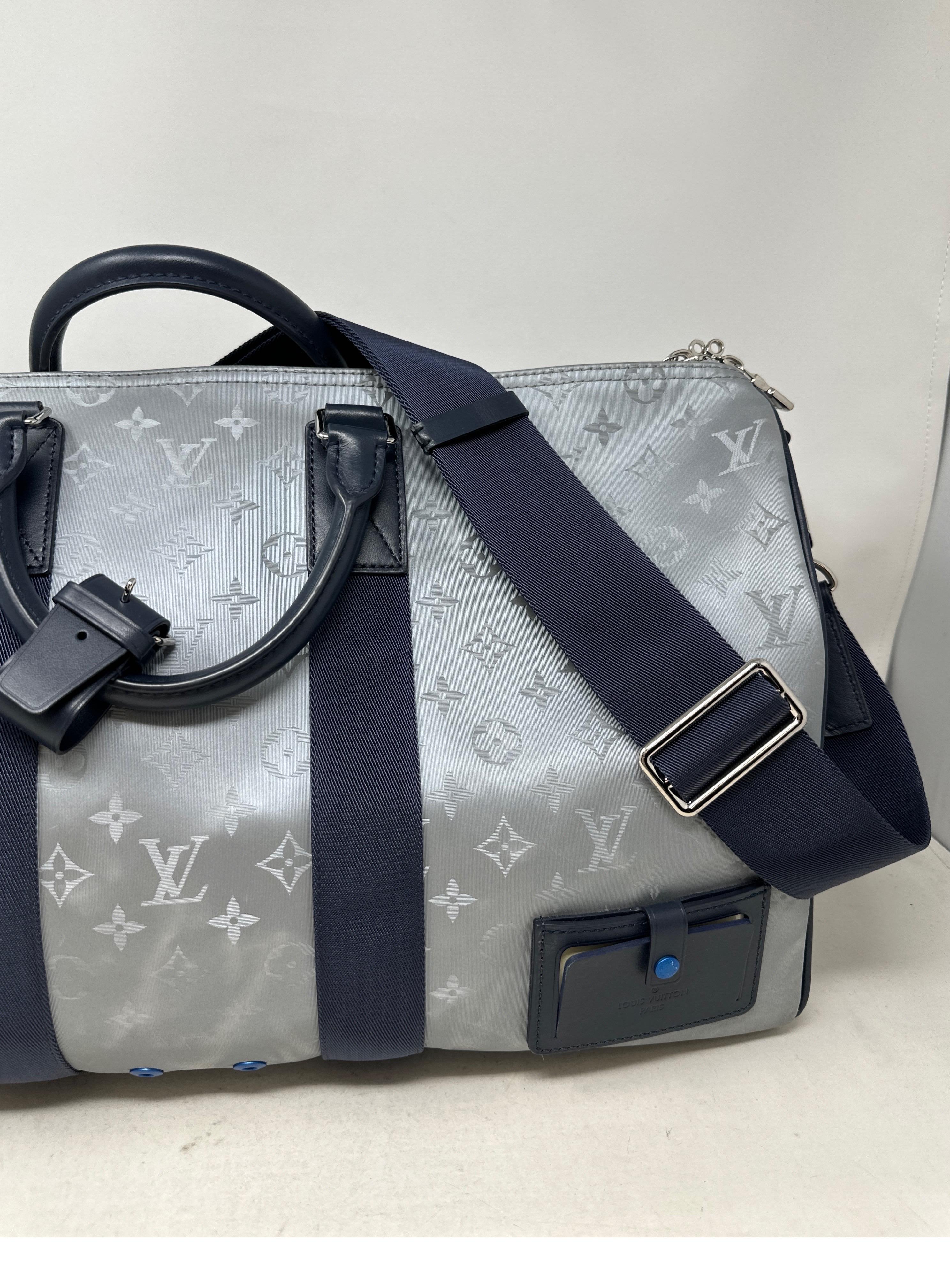 Louis Vuitton Silver Monogram Satellite 50 Keepall Bandouliere. Limited edition and rare collector's piece. Excellent condition. Interior clean. Unique silver grey coating over monogram. Navy leather handles and trim. Great carry on size for travel.