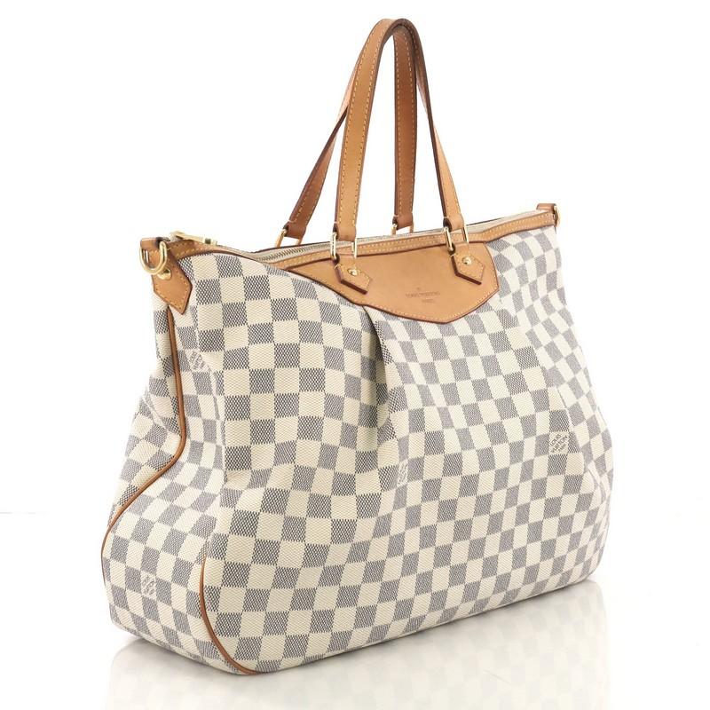 This Louis Vuitton Siracusa Handbag Damier GM, crafted in damier azur coated canvas, features vachetta leather strap and trim, pleated silhouette, and gold-tone hardware. Its zip closure opens to a beige fabric interior with slip pockets.