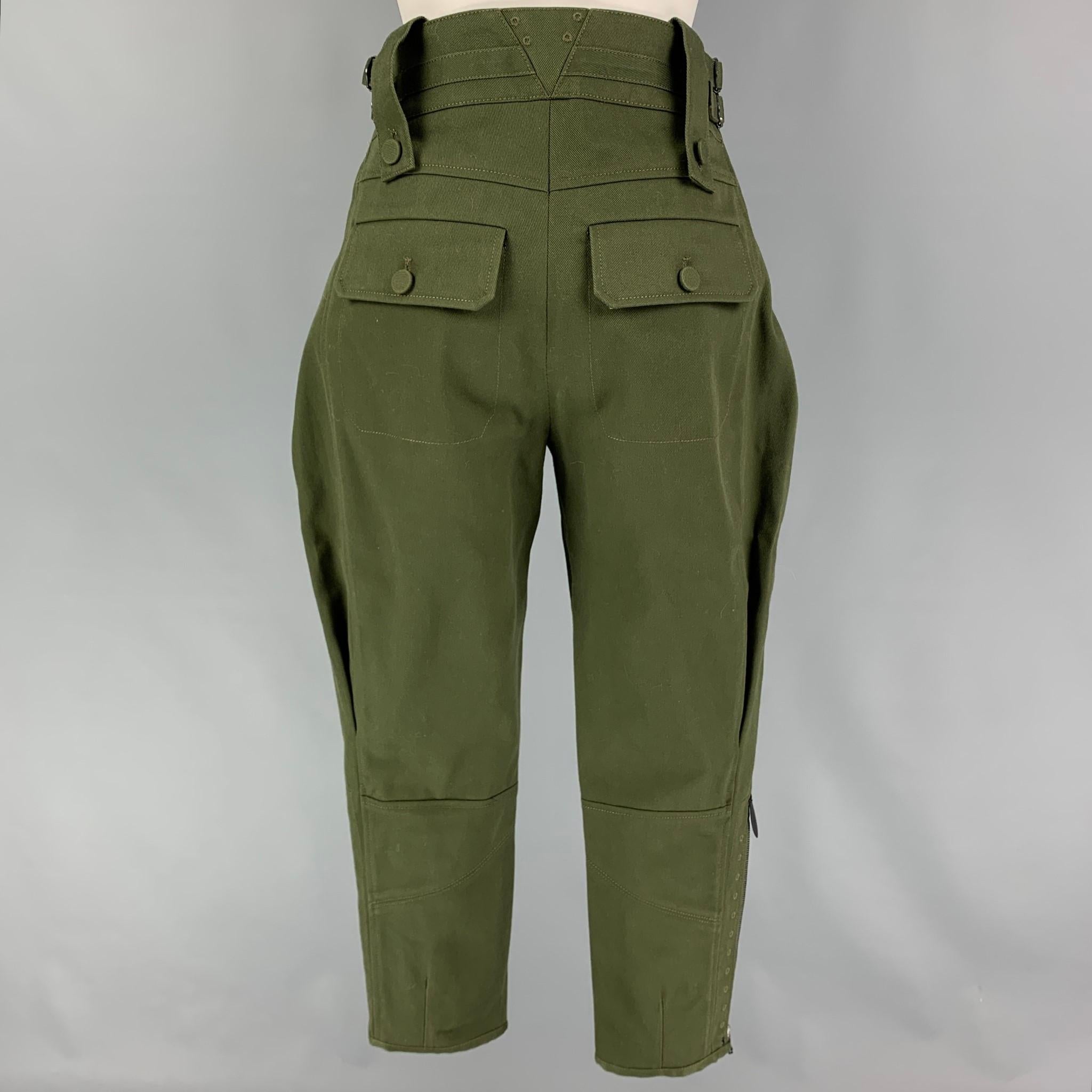 LOUIS VUITTON 'Tailored Jodhpurs' pants comes in a olive cotton / polyester featuring a calf-length jodhpurs design, adjustable high waist, gold tone trim buttons, side zippers, LV canvas tab detail, and a button fly closure. Made in