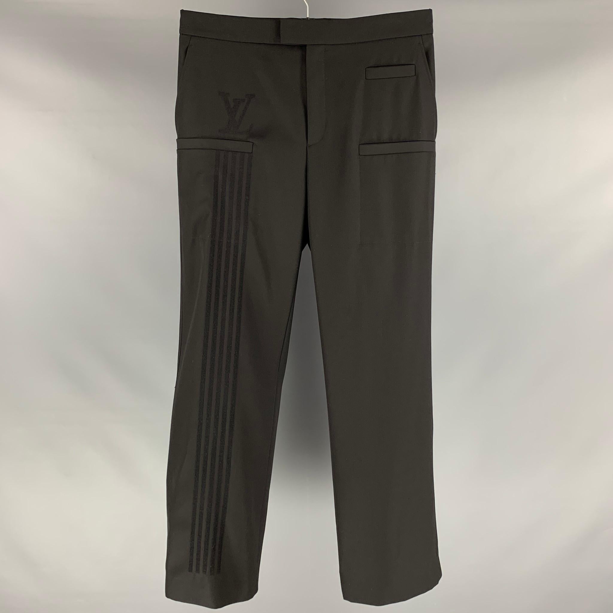 LOUIS VUITTON dress pants comes in a black polyester and wool material featuring a flat front, 3 pockets at front, logo applique detail right leg, medium waist style, front tab, and a zip fly closure. Made in Italy.

Excellent Pre-Owned