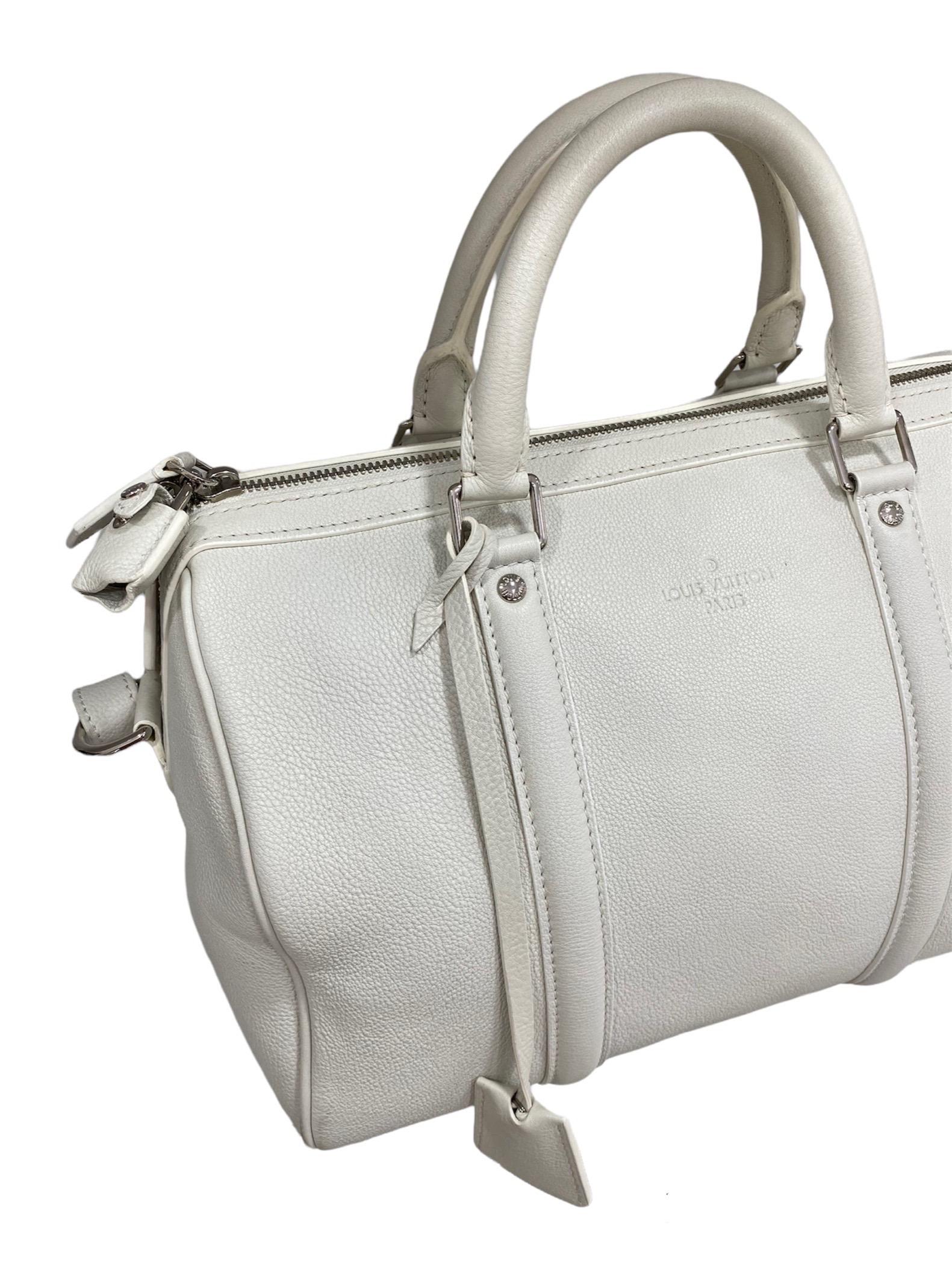 Sac cartable Louis Vuitton, modèle Sofia, taille 30, en cuir lisse blanc avec des éléments métalliques argentés.

Équipé d'une fermeture à glissière, doublé à l'intérieur en daim gris, très spacieux.

Équipé d'une double poignée rigide en cuir et