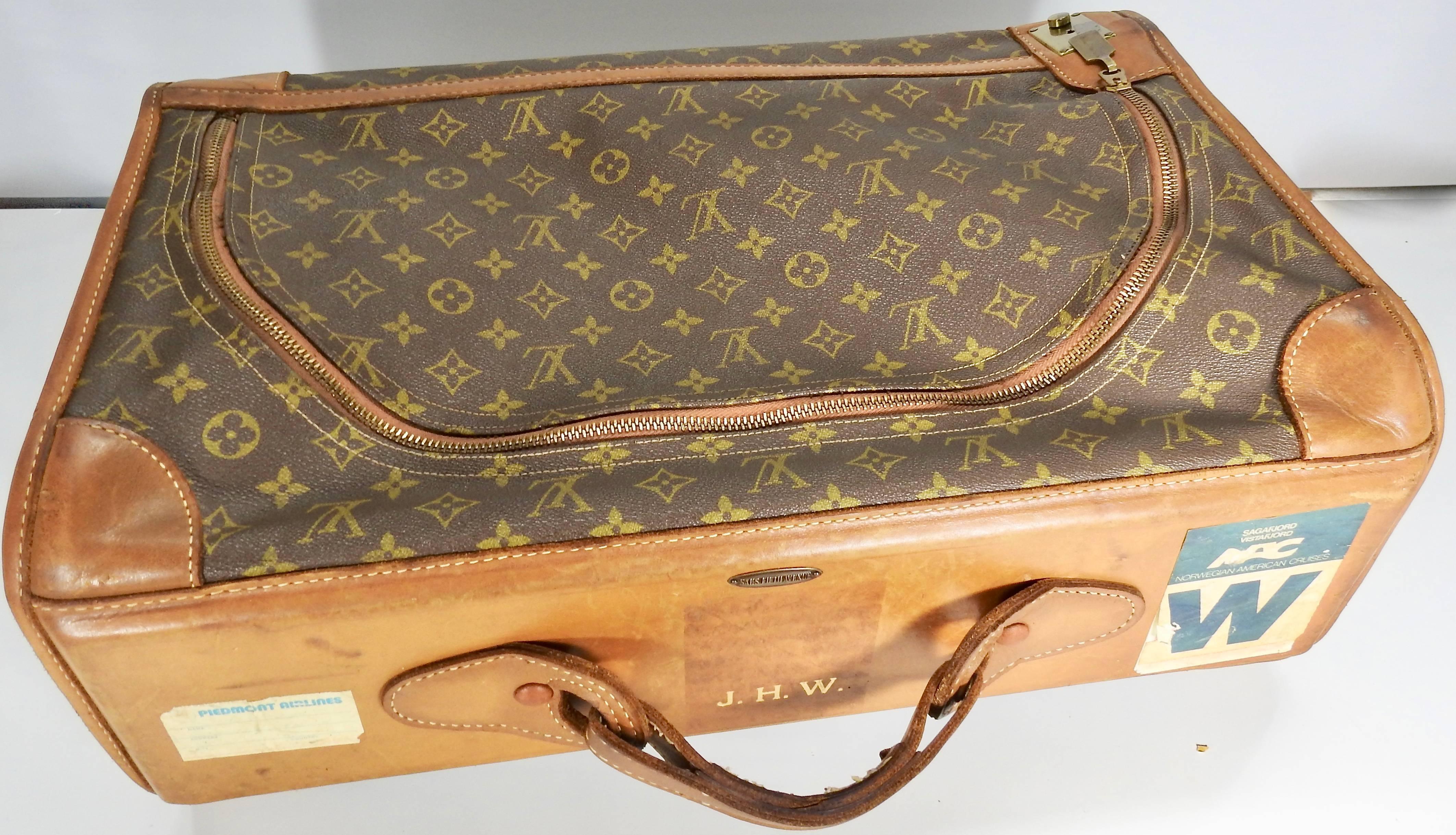We are offering a Classic Louis Vuitton soft overnight case. It has the initials J.H.W. along with a metal tag from Saks Fifth Avenue. It features a leather designer handle. The bag has a full length zipper with a key lock with a key. The brown