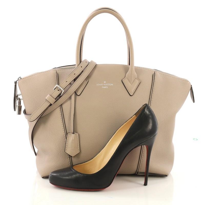 This Louis Vuitton Soft Lockit Handbag Leather PM, crafted from beige leather, features dual rolled handles, curved top, LV padlock on its side, and silver-tone hardware. Its top zip closure opens to a taupe suede interior with zip and slip pockets.