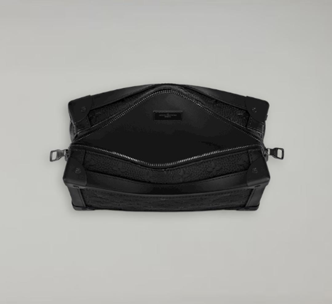 Réinterprétation du modèle messager classique, ce sac Soft Trunk est habillé de cuir Taurillon noir avec un motif Monogram embossé et est équipé d'une fermeture à glissière et d'une bandoulière de sac noir mat. Ses coins renforcés et sa forme carrée