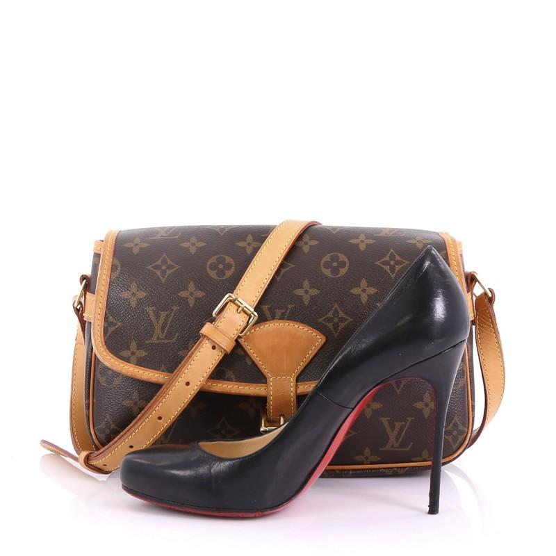 This Louis Vuitton Sologne Handbag Monogram Canvas, crafted from brown monogram coated canvas, features an adjustable vachetta leather shoulder strap, exterior back slip pocket, and gold-tone hardware. Its belted buckle closure opens to a brown