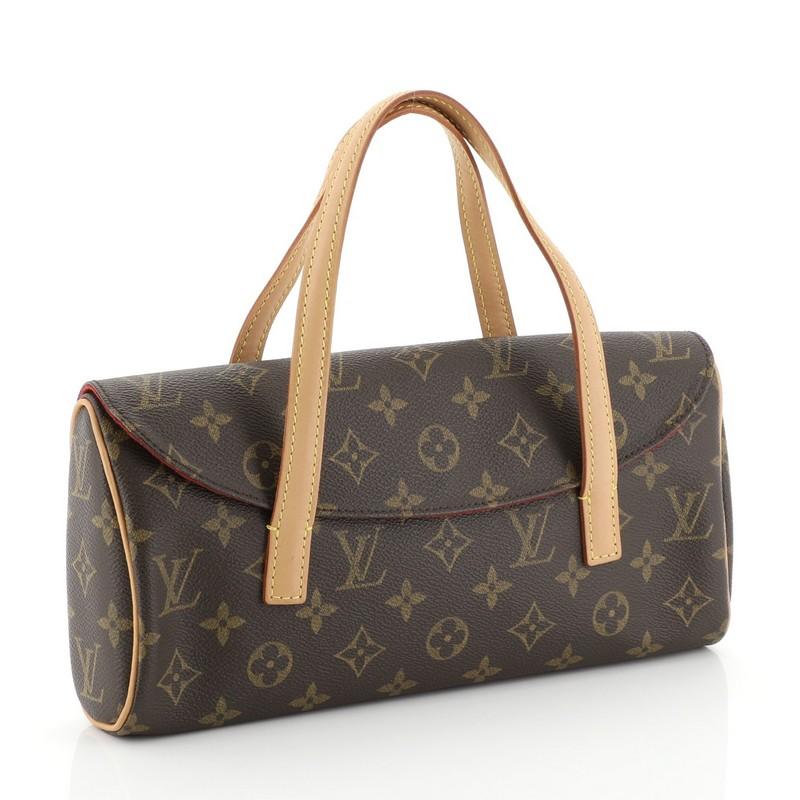 This Louis Vuitton Sonatine Handbag Monogram Canvas, crafted from brown monogram coated canvas, features dual flat vachetta leather handles, vachetta leather trim, and gold-tone hardware. Its hidden magnetic snap closure opens to a red microfiber