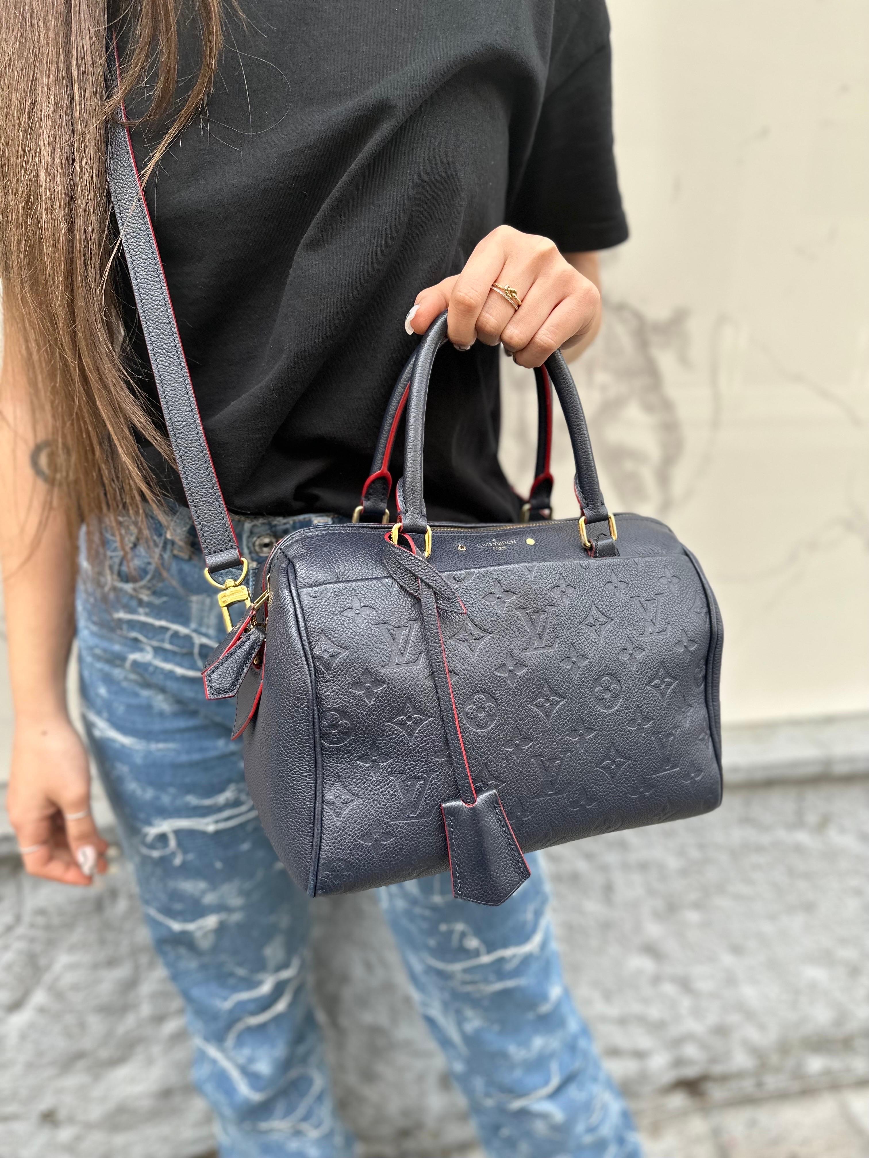 Bag by Louis Vuitton, Speedy Empreinte model, size 25, made of midnight blue leather in the classic Monogram pattern with red leather trim and gold hardware. Equipped with a double carriage zip top closure and a front pocket. Equipped with a double