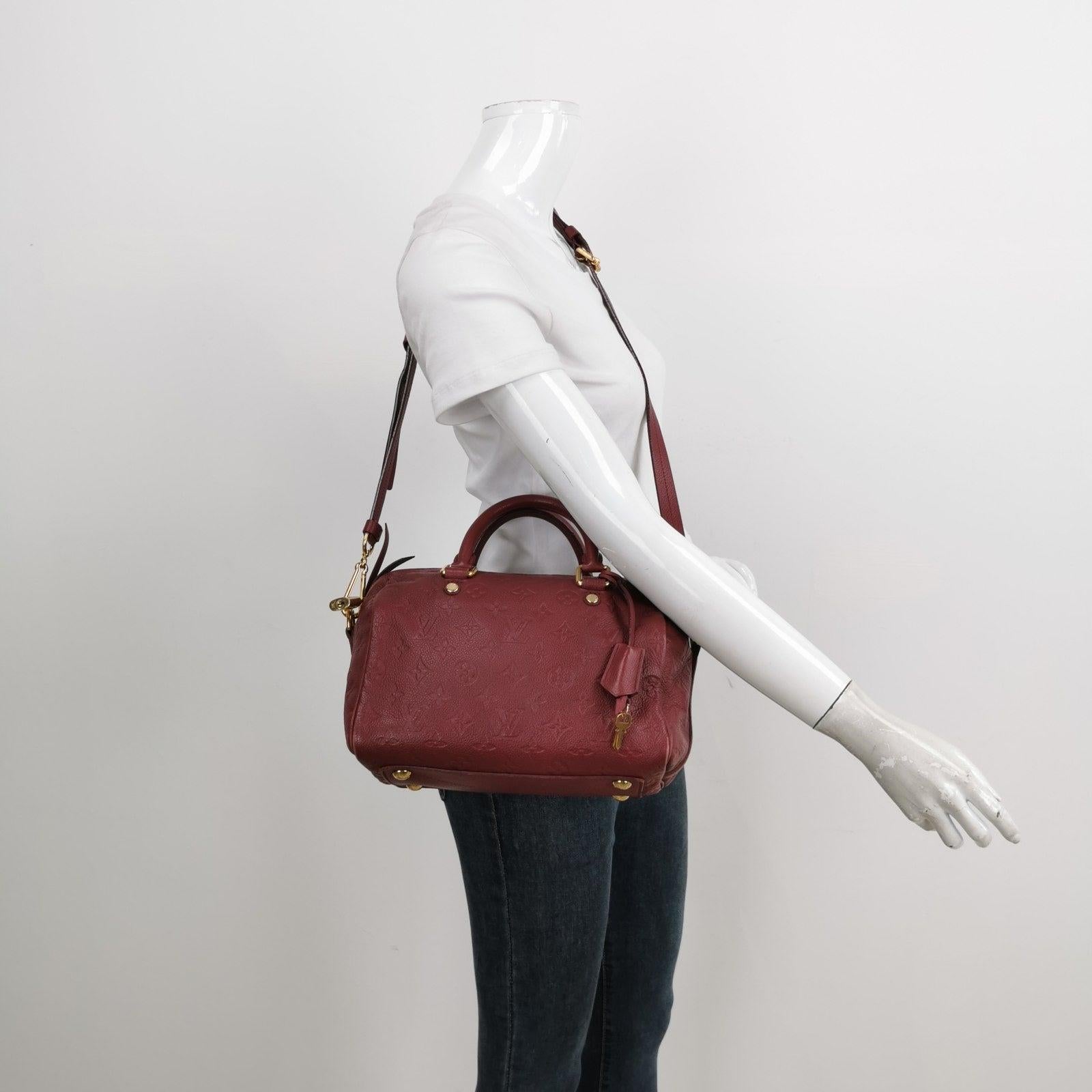 Louis Vuitton Speedy 25 Bandouliere Empreinte Leather Burgundy These are professional photos of the actual bag offered by Luxbags. The Louis Vuitton Speedy is a renowned design from the French luxury brand Louis Vuitton. This particular version