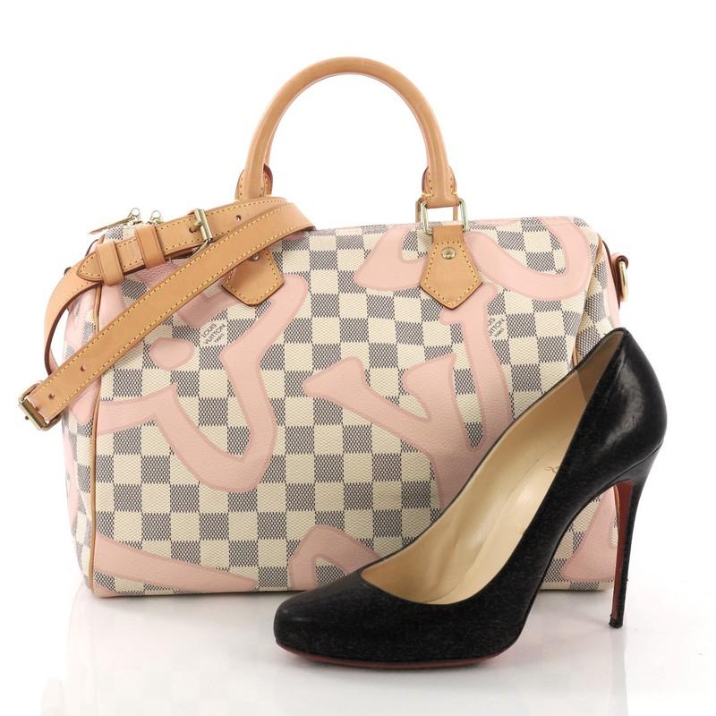 This Louis Vuitton Speedy Bandouliere Bag Limited Edition Damier Tahitienne 30, crafted from tahitienne damier azur coated canvas, features dual rolled handles, leather trims, and gold-tone hardware. Its zip closure opens to a pink fabric interior