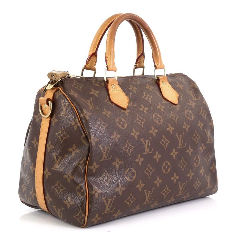 This Louis Vuitton Speedy Bandouliere Bag Monogram Canvas 30, crafted from brown monogram coated canvas, features dual rolled top handles and gold-tone hardware. Its zip closure opens to a brown fabric interior with side slip pocket. Authenticity