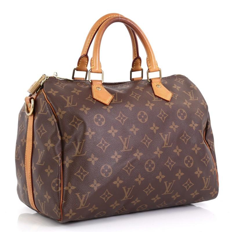 This Louis Vuitton Speedy Bandouliere Bag Monogram Canvas 30, crafted from brown monogram coated canvas, features dual rolled top handles and gold-tone hardware. Its zip closure opens to a brown fabric interior with side slip pocket. Authenticity