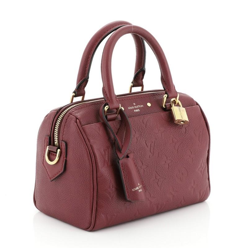 This Louis Vuitton Speedy Bandouliere NM Handbag Monogram Empreinte Leather 20, crafted from purple monogram empreinte leather, features dual rolled leather handles and gold-tone hardware. Its two-way zip closure opens to a purple fabric interior