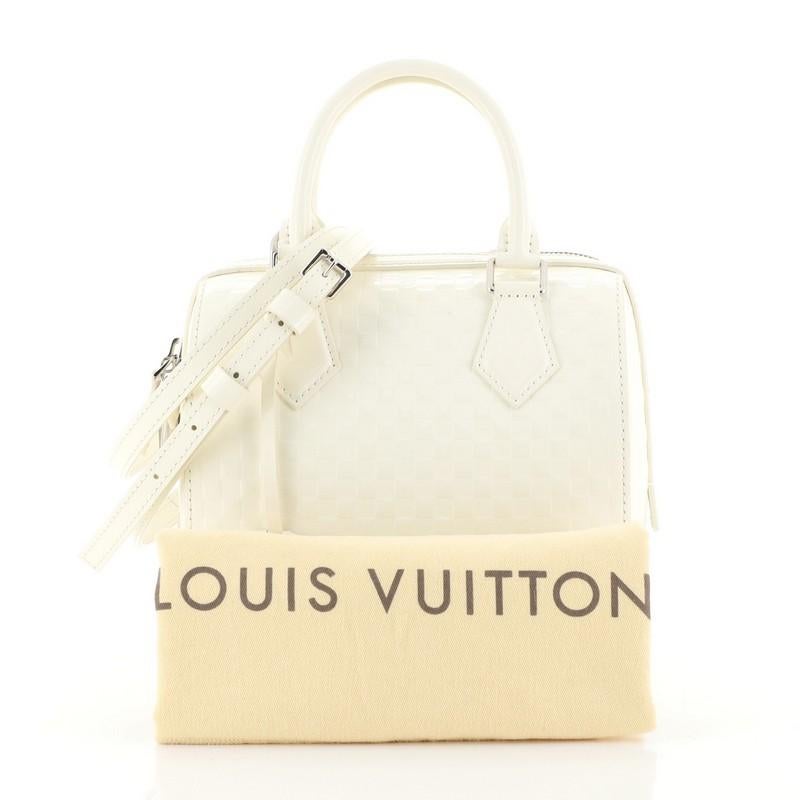 This Louis Vuitton Speedy Cube Bag Damier Facette PM, crafted from white damier facette, features dual rolled handles, protective base studs and silver-tone hardware. Its two-way zip closure opens to a white microfiber interior with slip pocket.