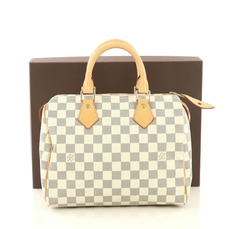 This Louis Vuitton Speedy Handbag Damier 25, crafted in damier azur coated canvas, features dual rolled handles, vachetta leather trim, and gold-tone hardware. Its top zip closure opens to a neutral fabric interior with slip pocket. Authenticity