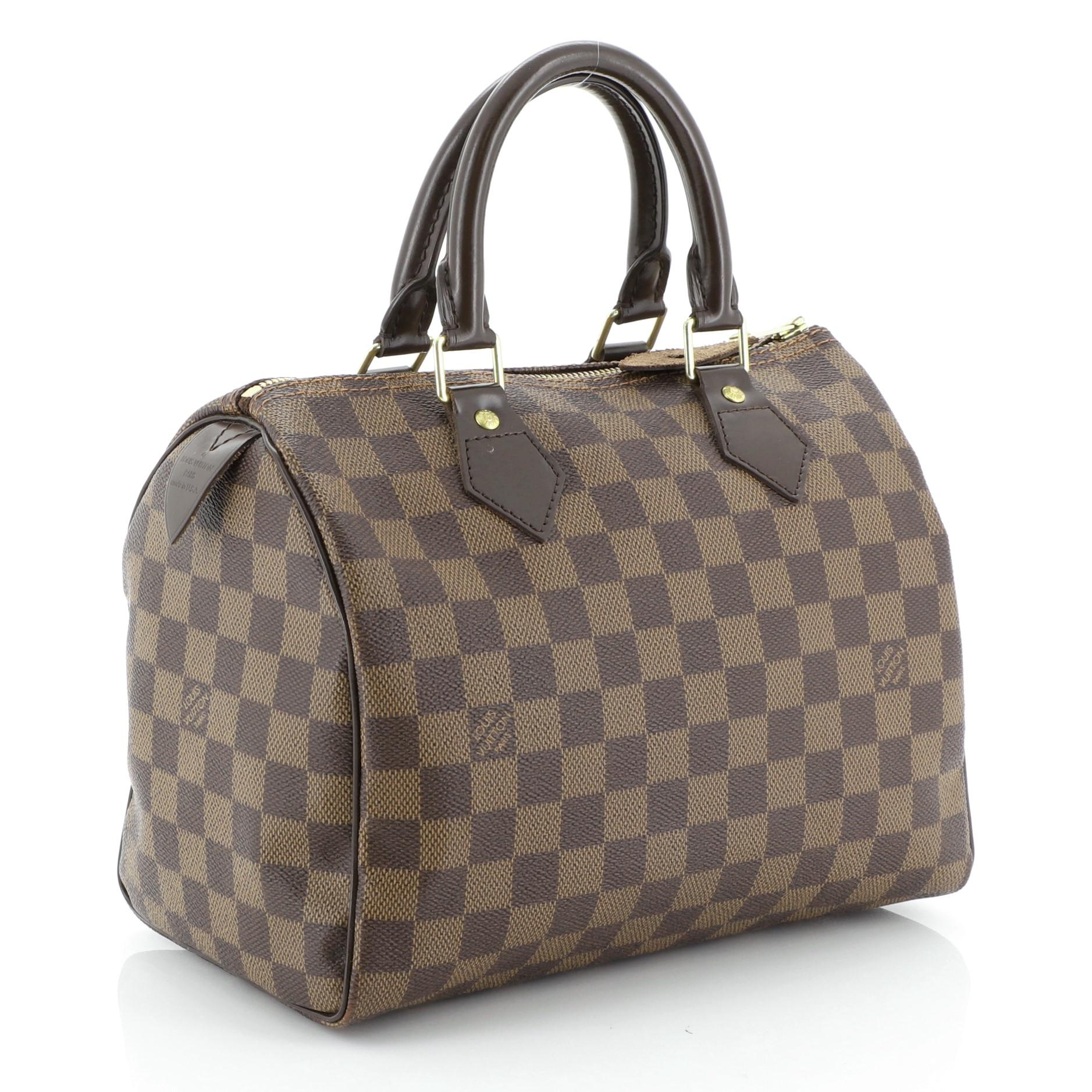 This Louis Vuitton Speedy Handbag Damier 25, crafted in damier ebene coated canvas, features dual rolled handles, vachetta leather trim, and gold-tone hardware. Its zip closure opens to a red fabric interior with slip pocket. Authenticity code