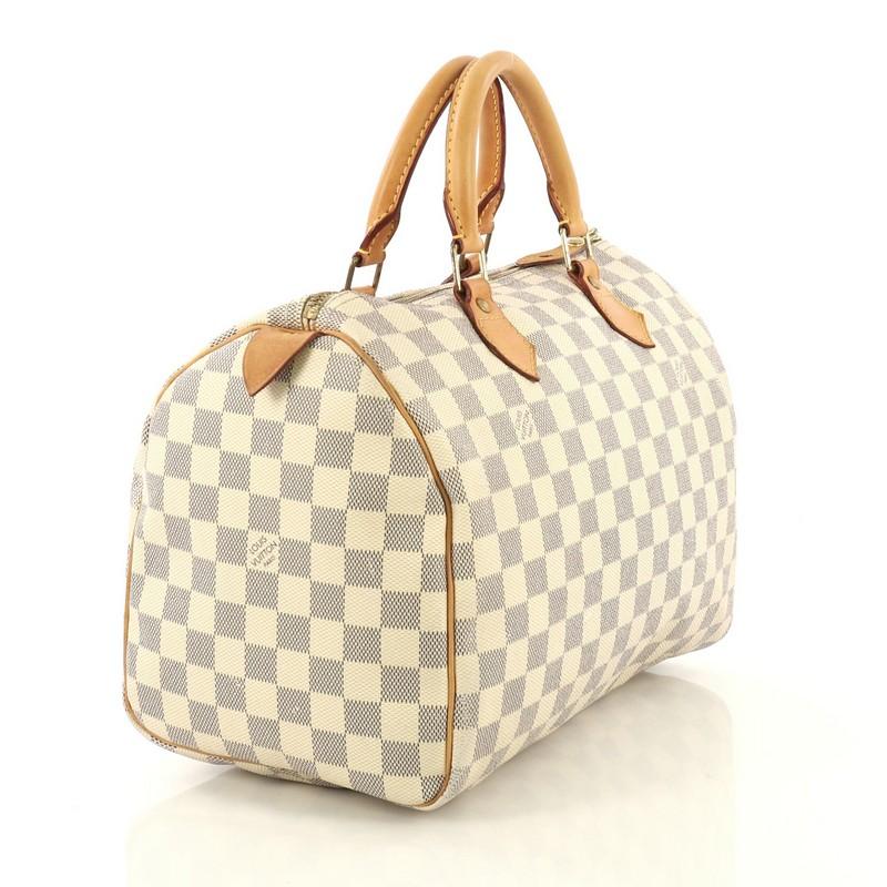 This Louis Vuitton Speedy Handbag Damier 30, crafted in damier azur coated canvas, features dual rolled handles, leather trim, and gold-tone hardware. Its zip closure opens to a neutral fabric interior with slip pocket. Authenticity code reads: