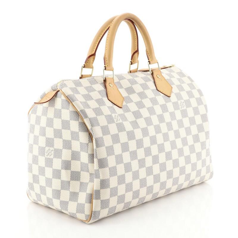 This Louis Vuitton Speedy Handbag Damier 30, crafted in damier azur coated canvas, features dual rolled handles, leather trim, and gold-tone hardware. Its zip closure opens to a neutral fabric interior with slip pocket. Authenticity code reads: