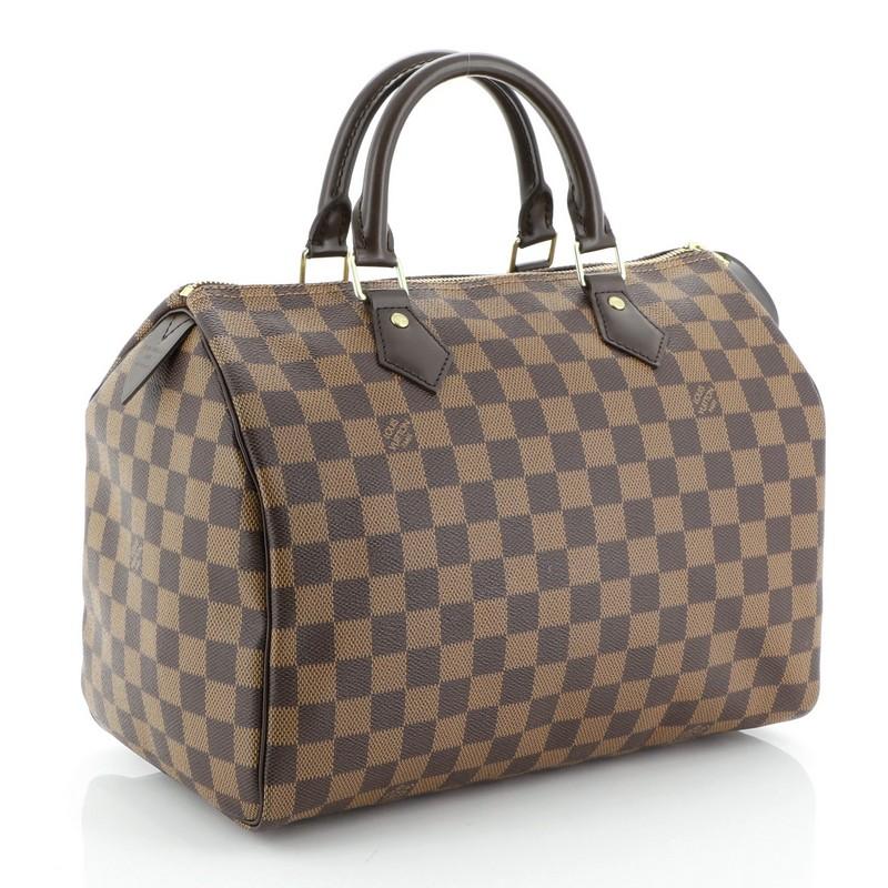 This Louis Vuitton Speedy Handbag Damier 30, crafted in damier ebene coated canvas, features dual rolled handles, leather trim, and gold-tone hardware. Its zip closure opens to a red fabric interior with slip pocket. Authenticity code reads: CT4124.