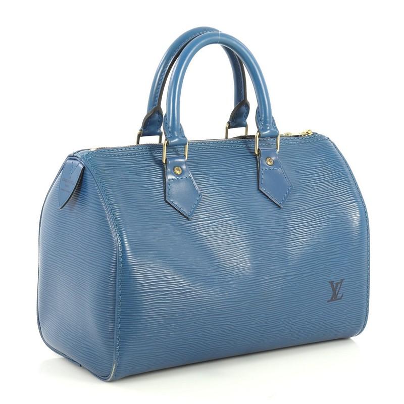 This Louis Vuitton Speedy Handbag Epi Leather 25, crafted from blue epi leather, features dual rolled leather handles, exterior side pocket, and gold-tone hardware. Its zip closure opens to a blue raw leather interior with slip pockets. Authenticity