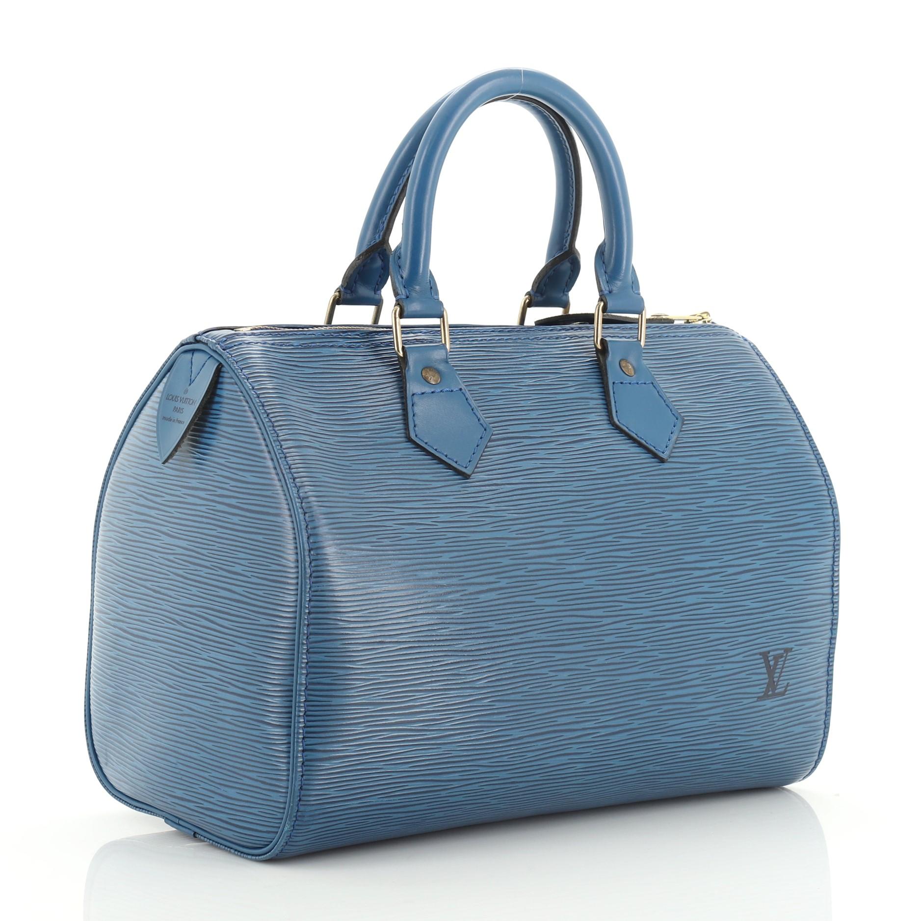 This Louis Vuitton Speedy Handbag Epi Leather 25 is an everyday bag designed as a smaller interpretation of the Keepall bag. Crafted from blue epi leather, features dual rolled leather handles, exterior side pocket, and gold-tone hardware. Its zip