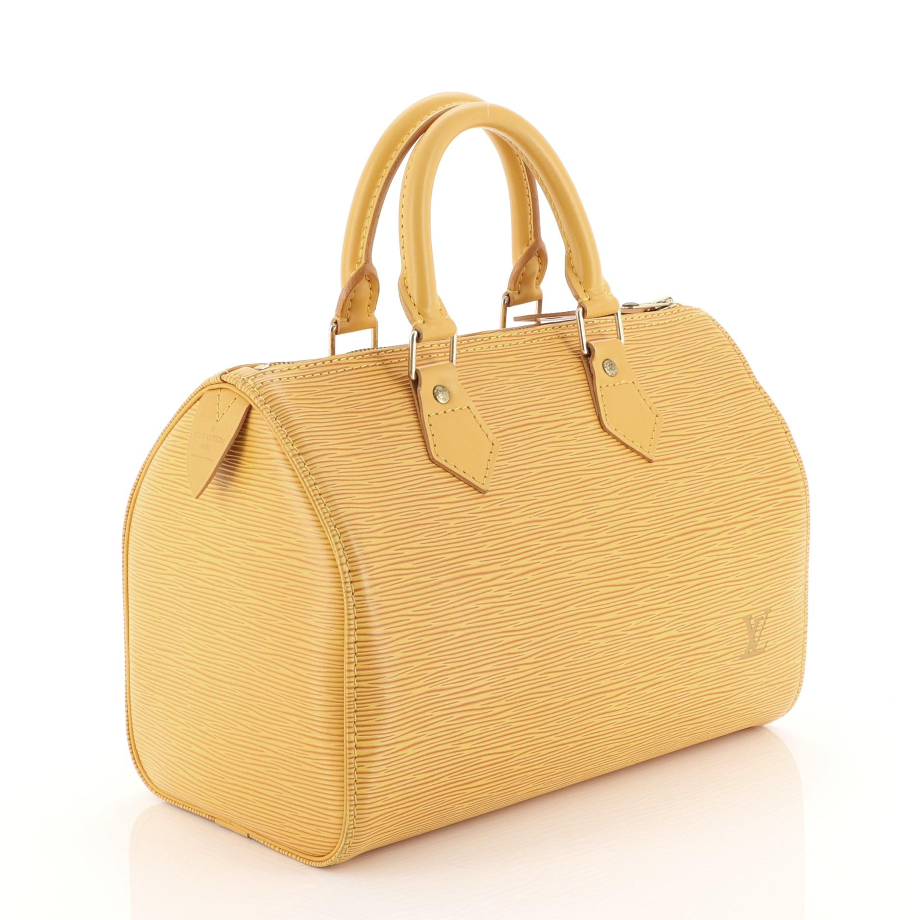 This Louis Vuitton Speedy Handbag Epi Leather 25, crafted from yellow epi leather, features dual rolled leather handles, exterior side pocket, and gold-tone hardware. Its zip closure opens to a yellow raw leather interior with slip pockets.